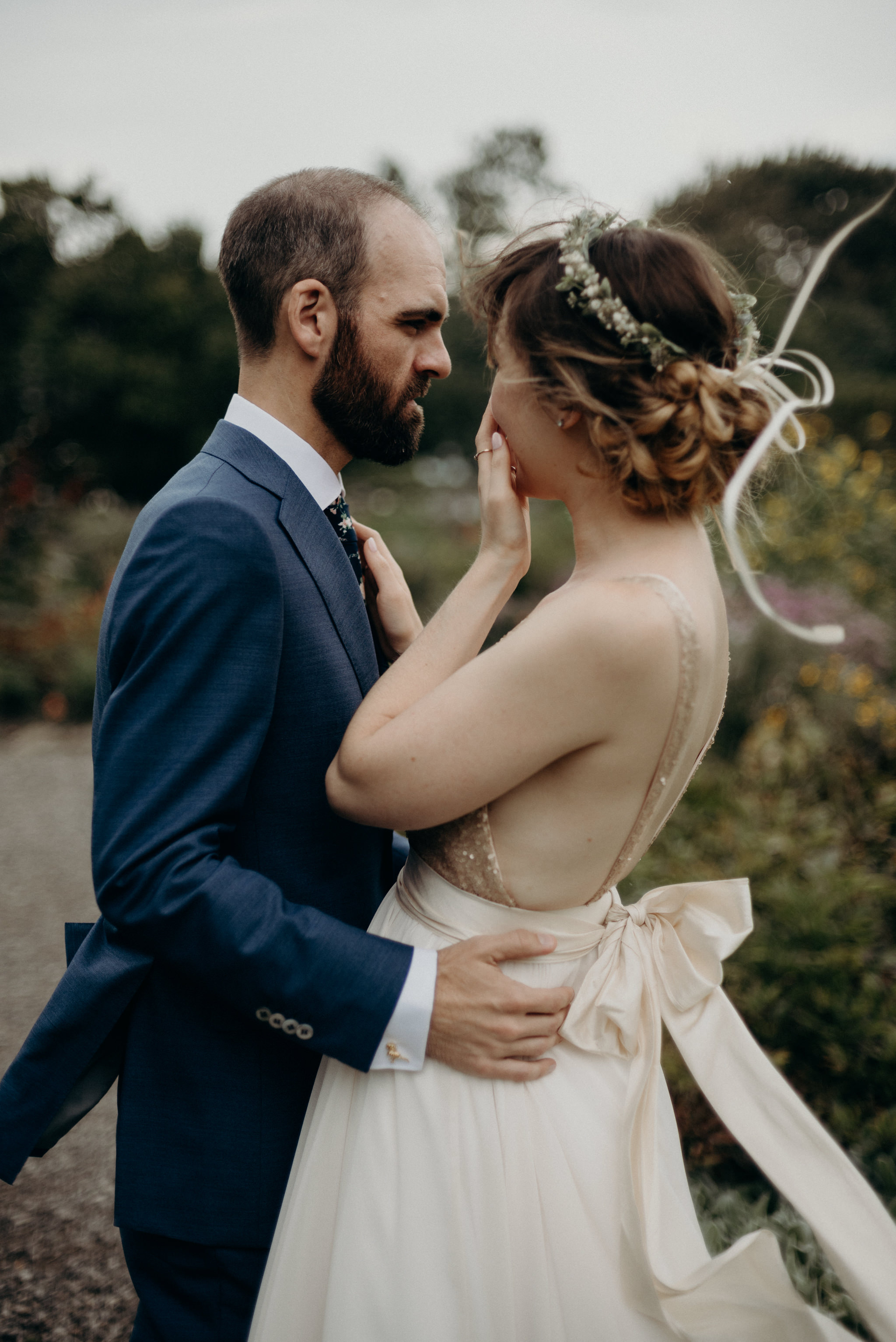 bride hugging groom in gardens on a windy day