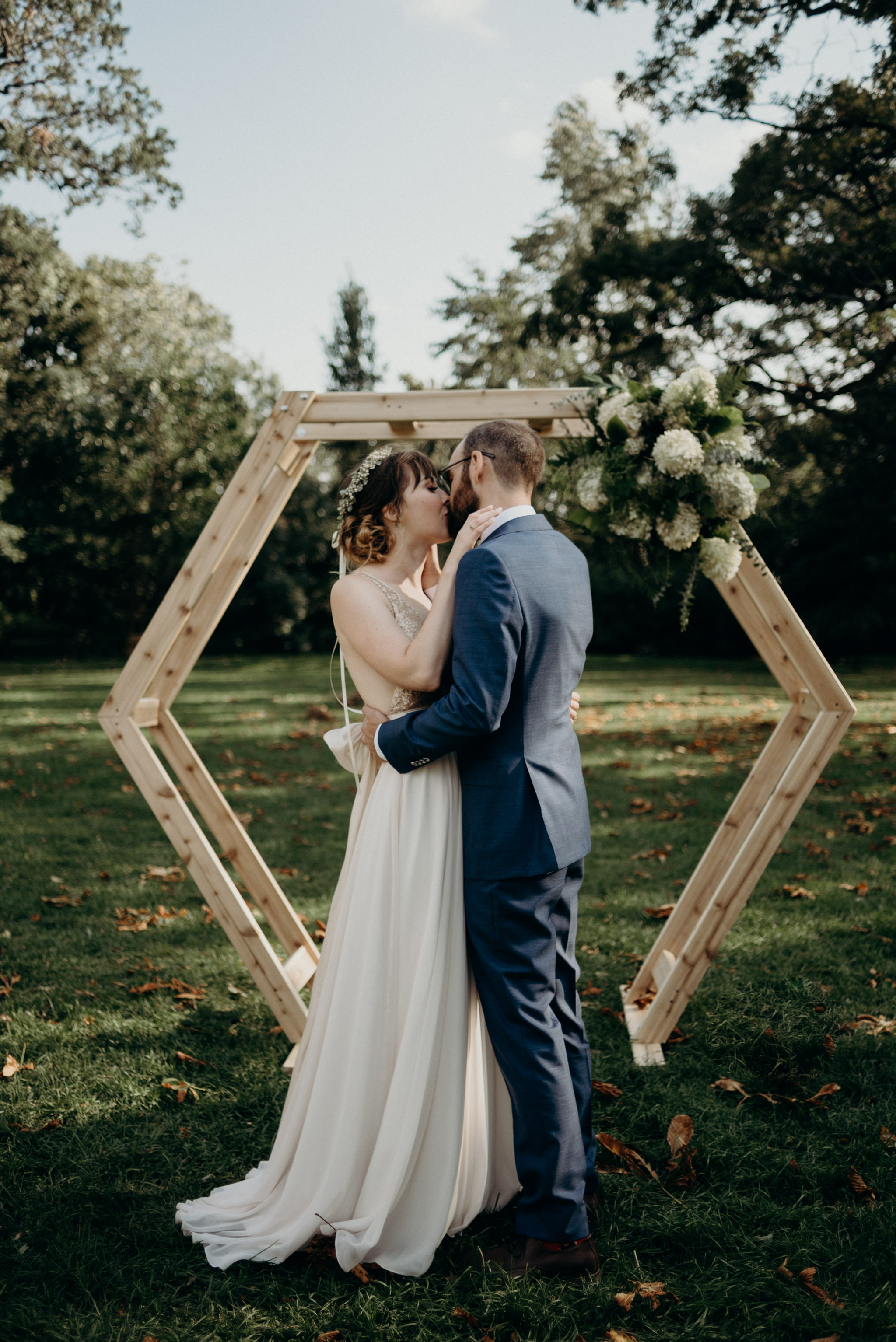 first kiss in front of wood hexagon backdrop during outdoor ceremony