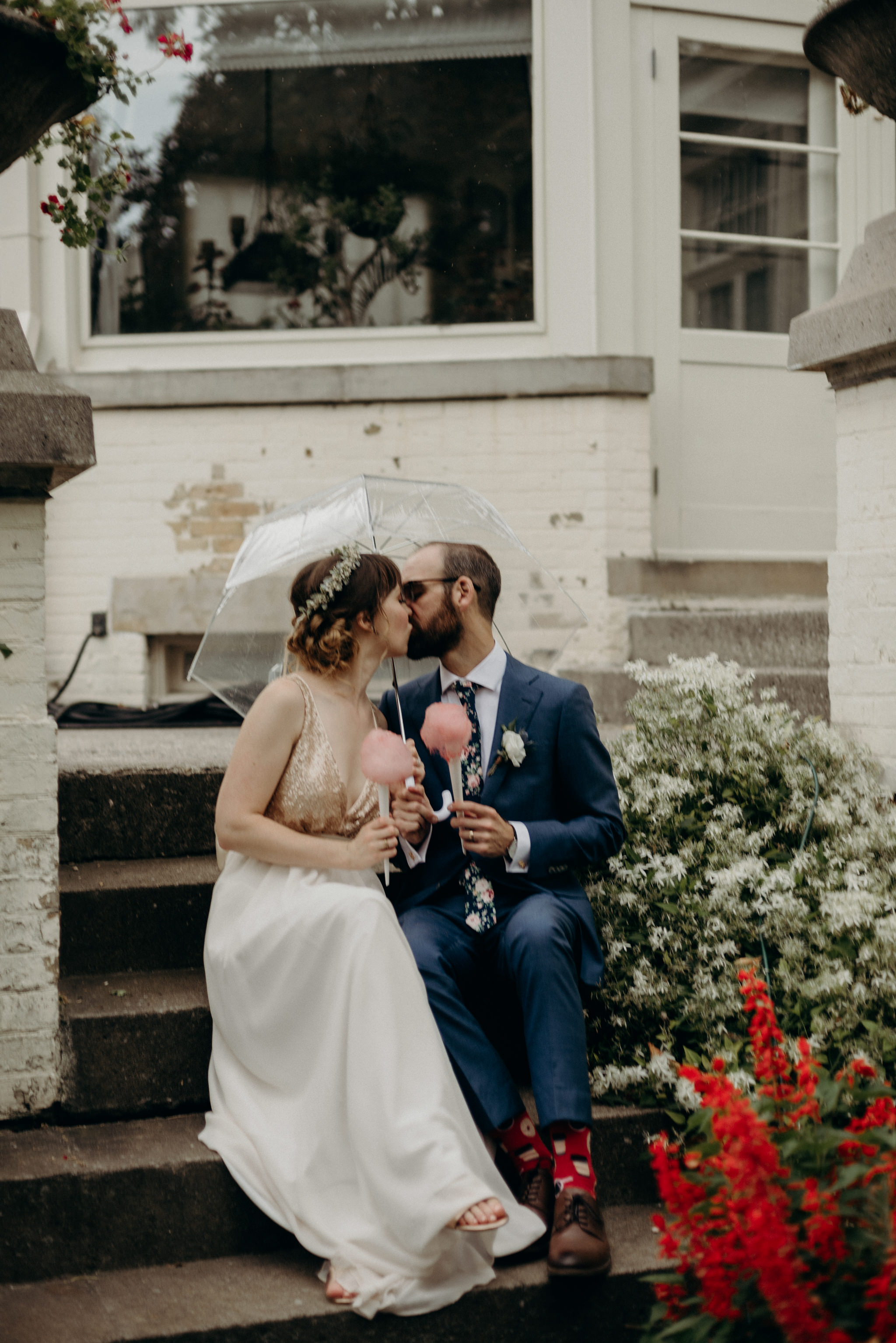 bride and groom sitting on steps of Spadina Museum holding cotton candy and kissing