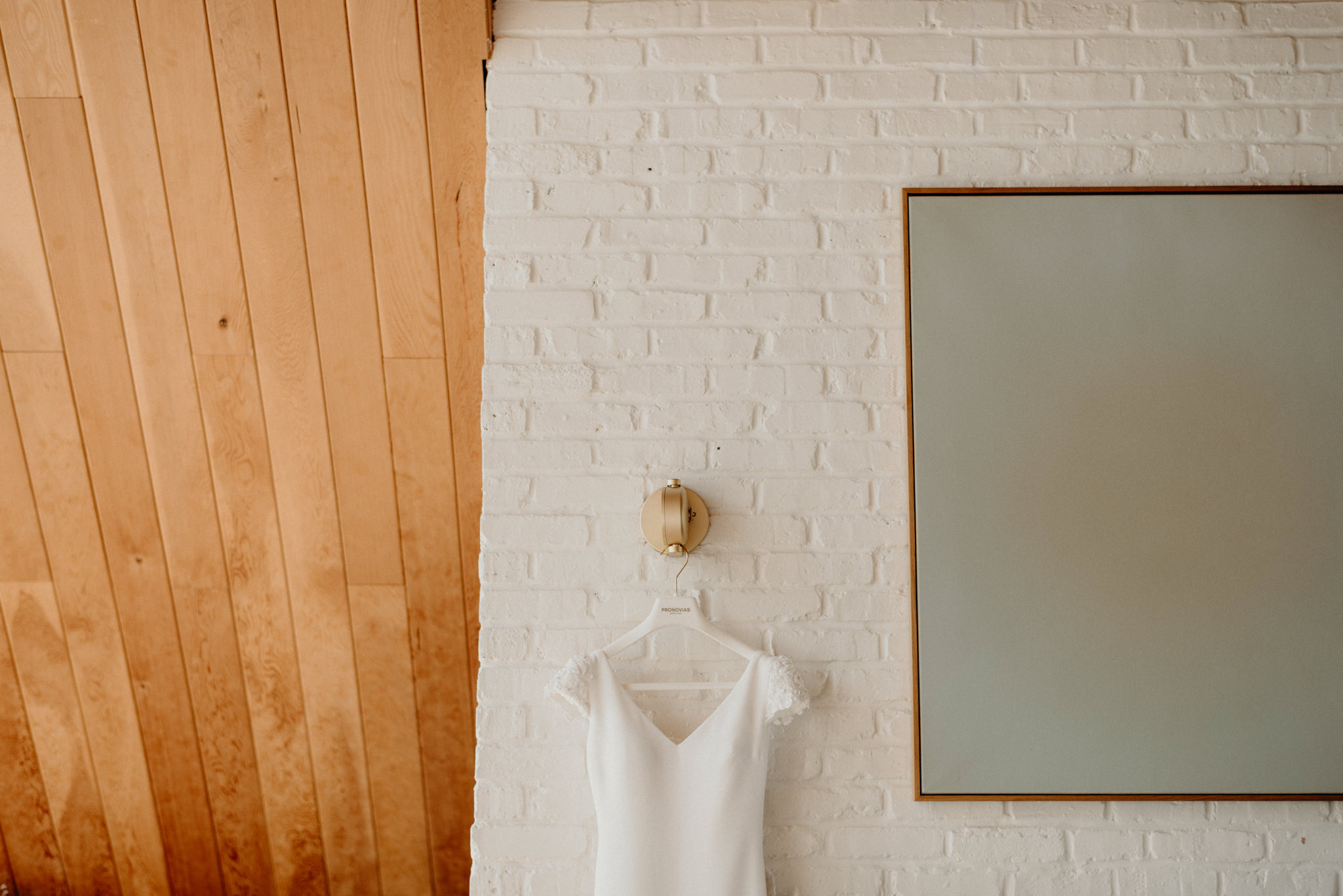 Pronovias wedding dressing hanging on white brick wall