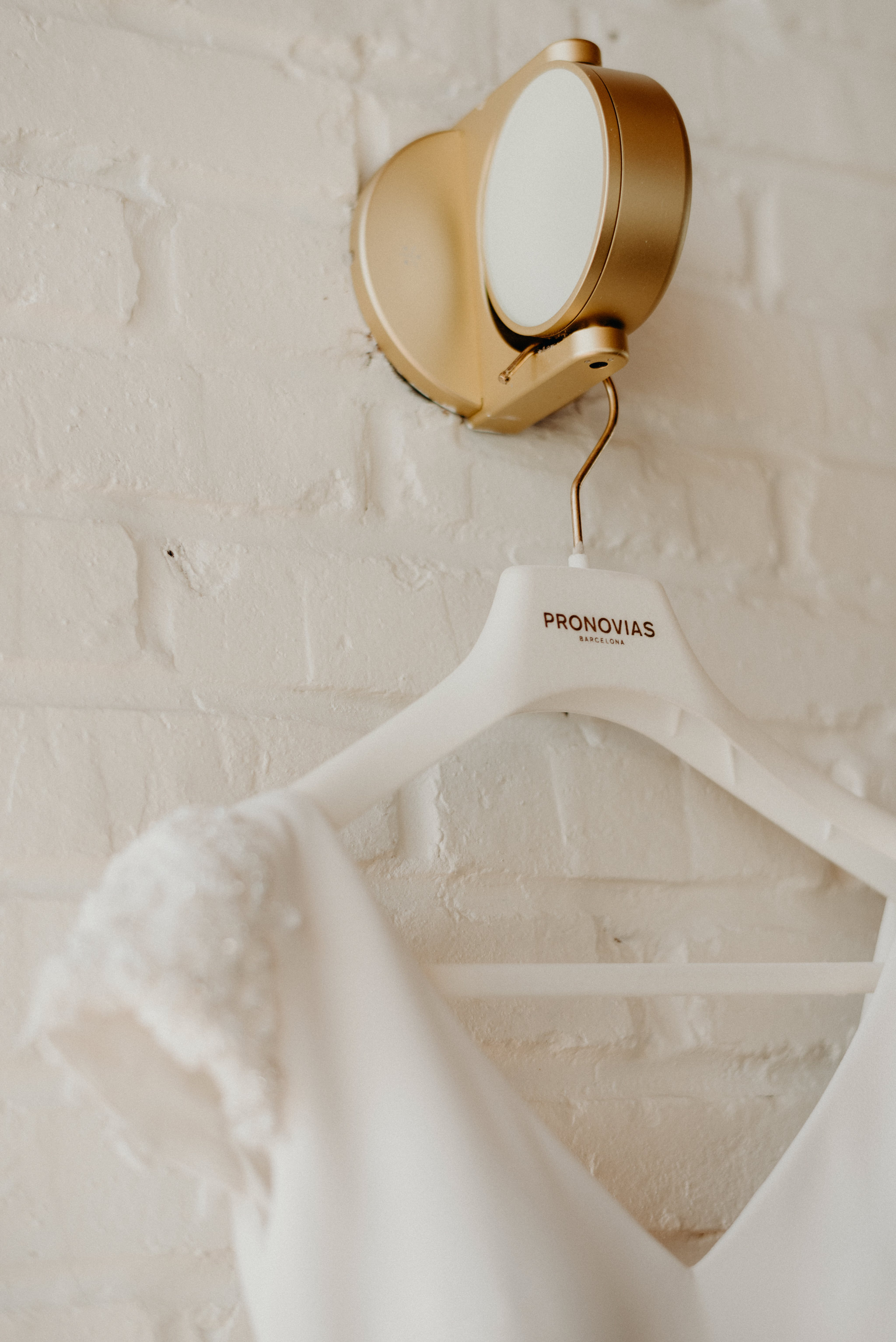 Pronovias wedding dressing hanging on white brick wall