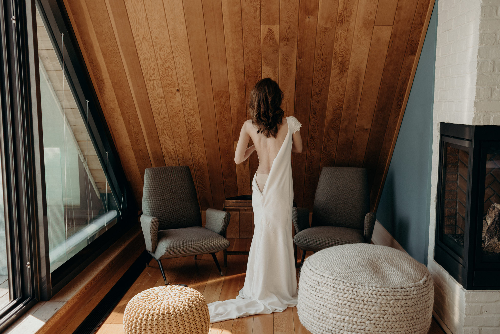 bride getting into dress in a-frame cabin room with large windows