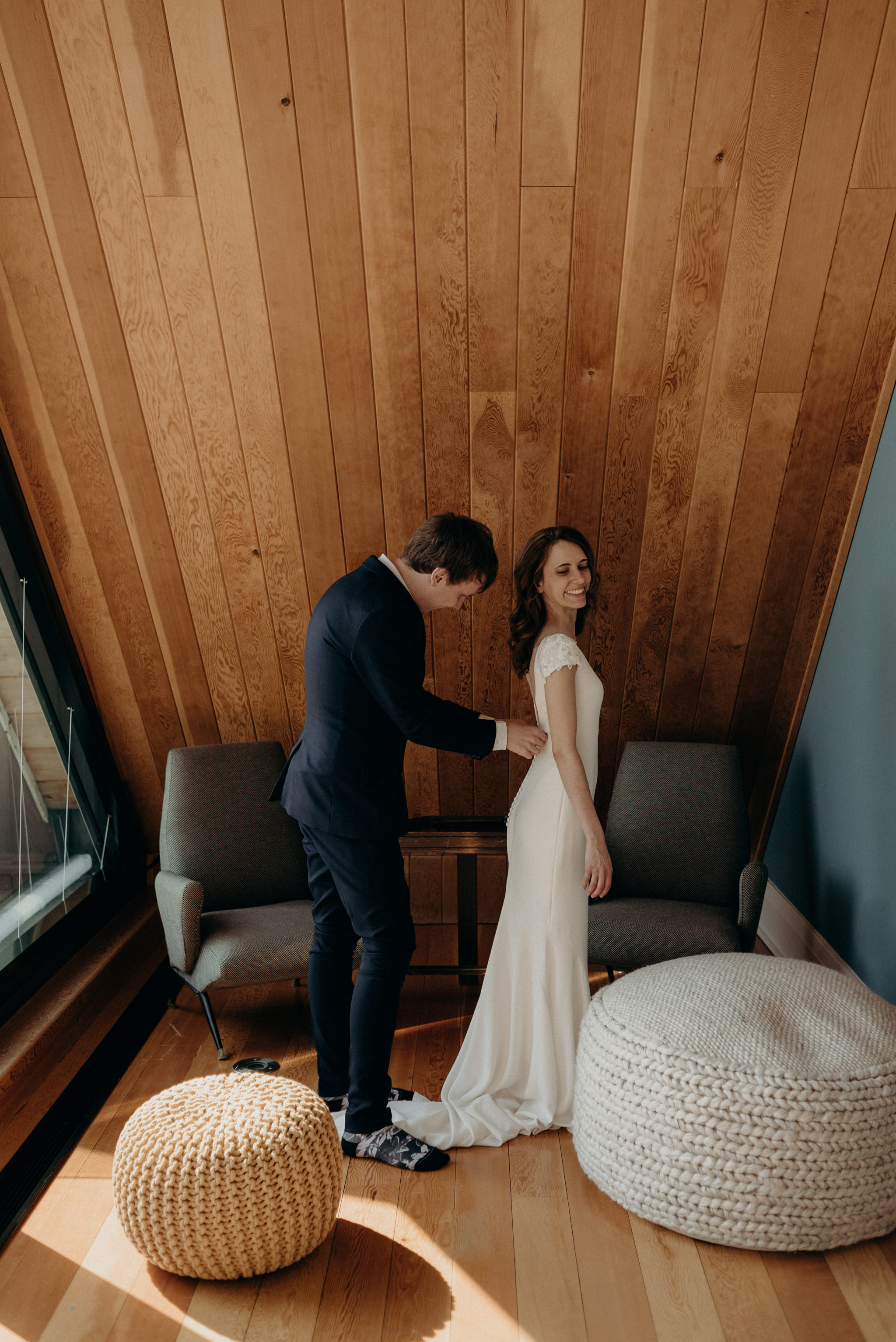 groom helping bride get into dress