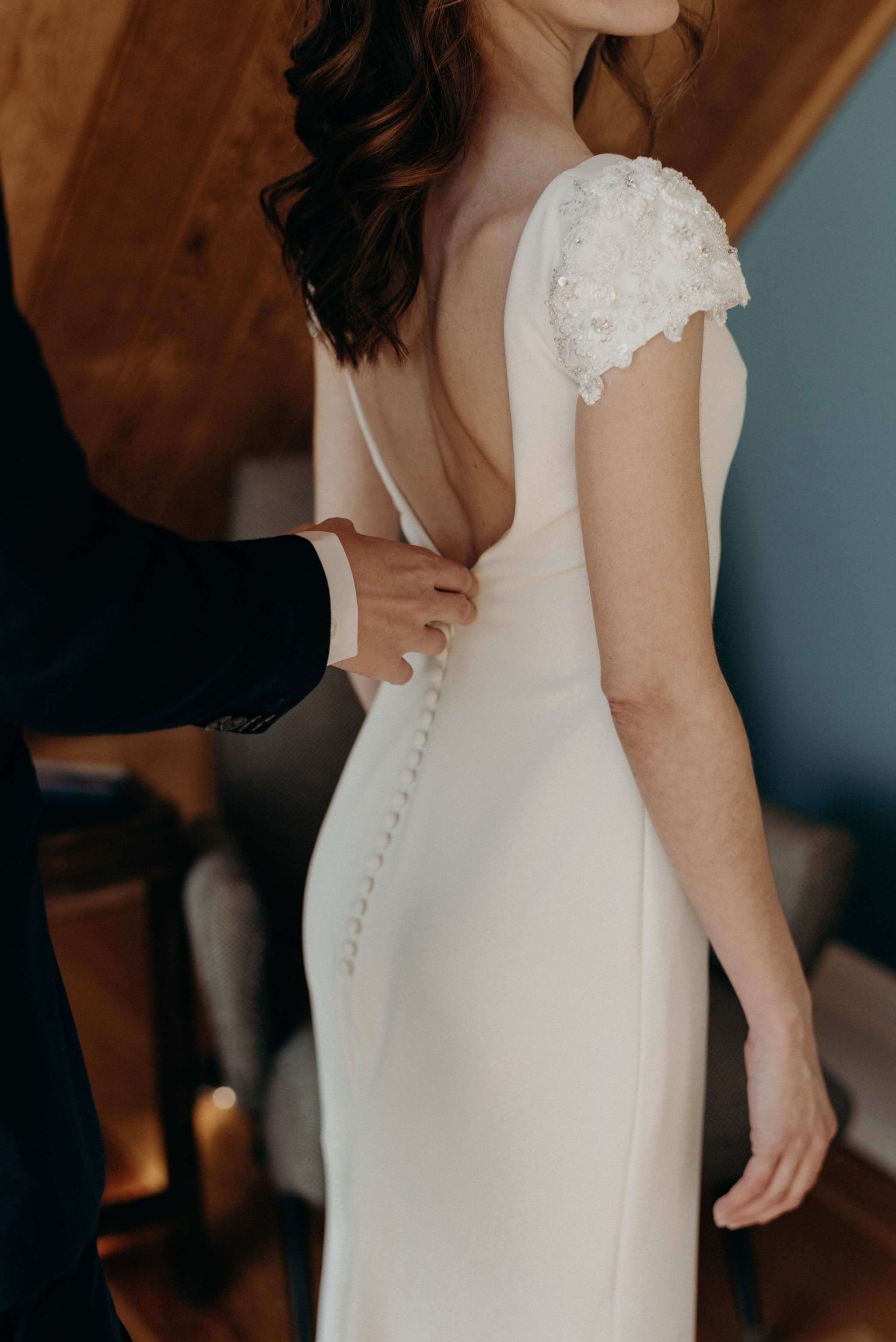 groom helping bride get into dress