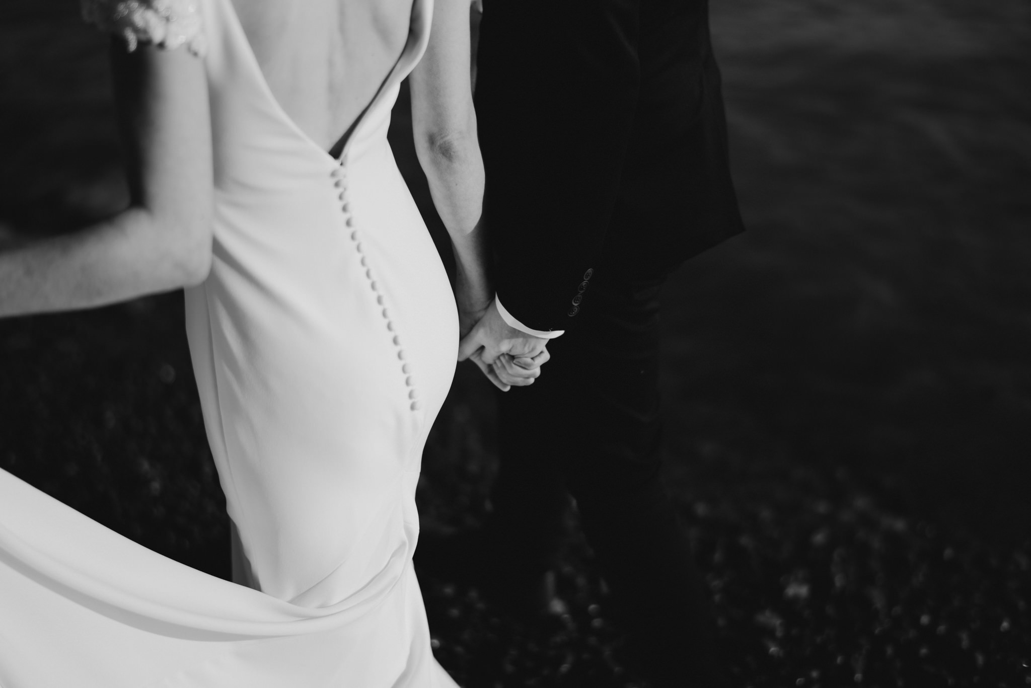 couple holding hands walking on beach