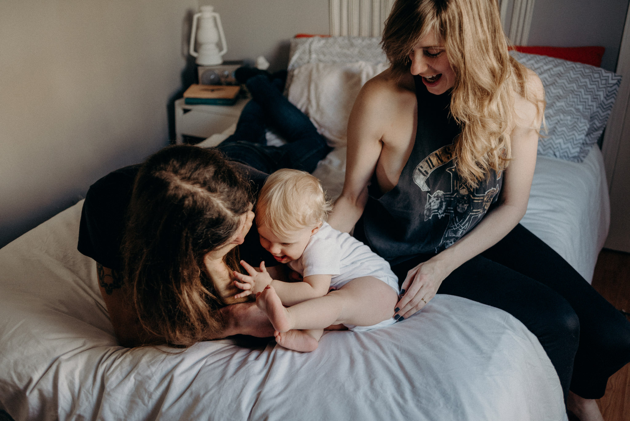 hip young couple playing with toddler on bed