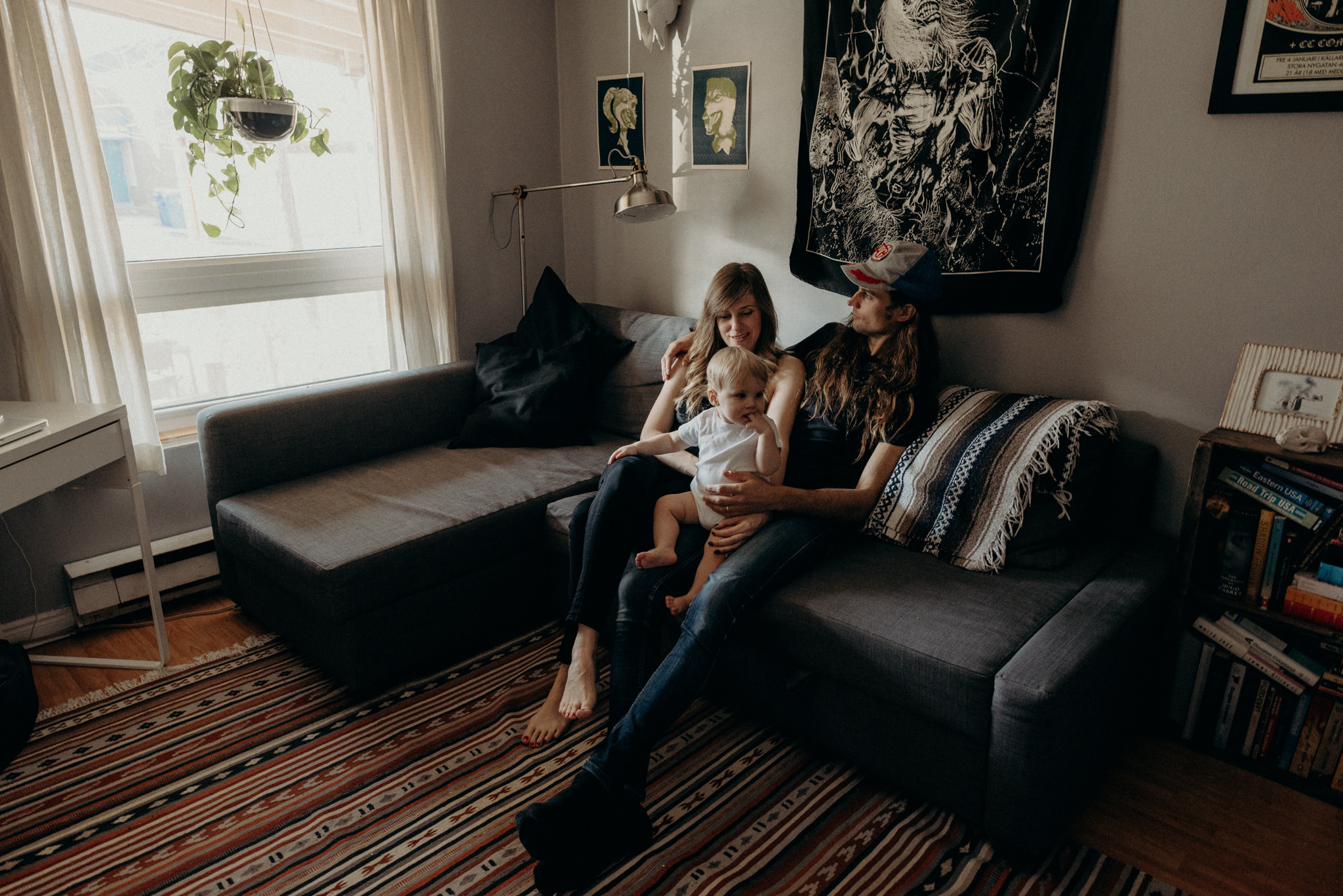 hip young couple sitting on couch in apartment with toddler