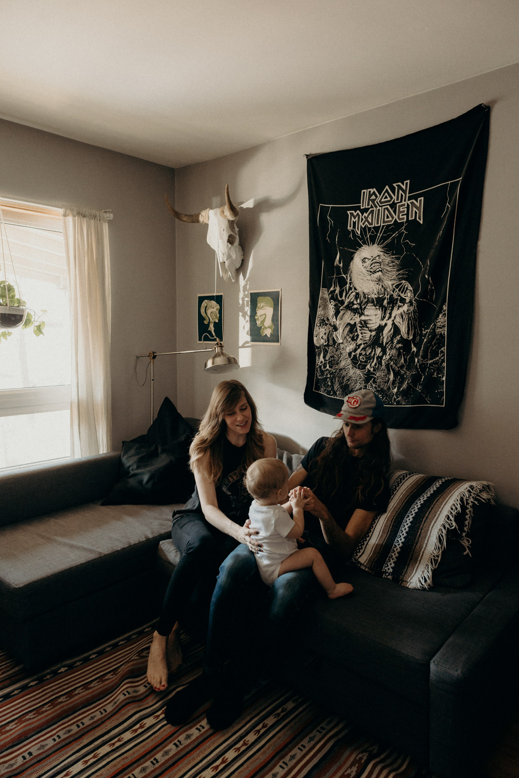 hip young couple sitting on couch in apartment with little boy