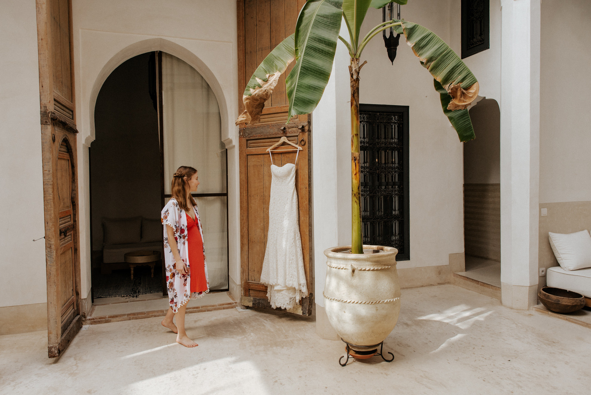 Bride and wedding dress hanging on door in Riad 42 for Morocco elopement