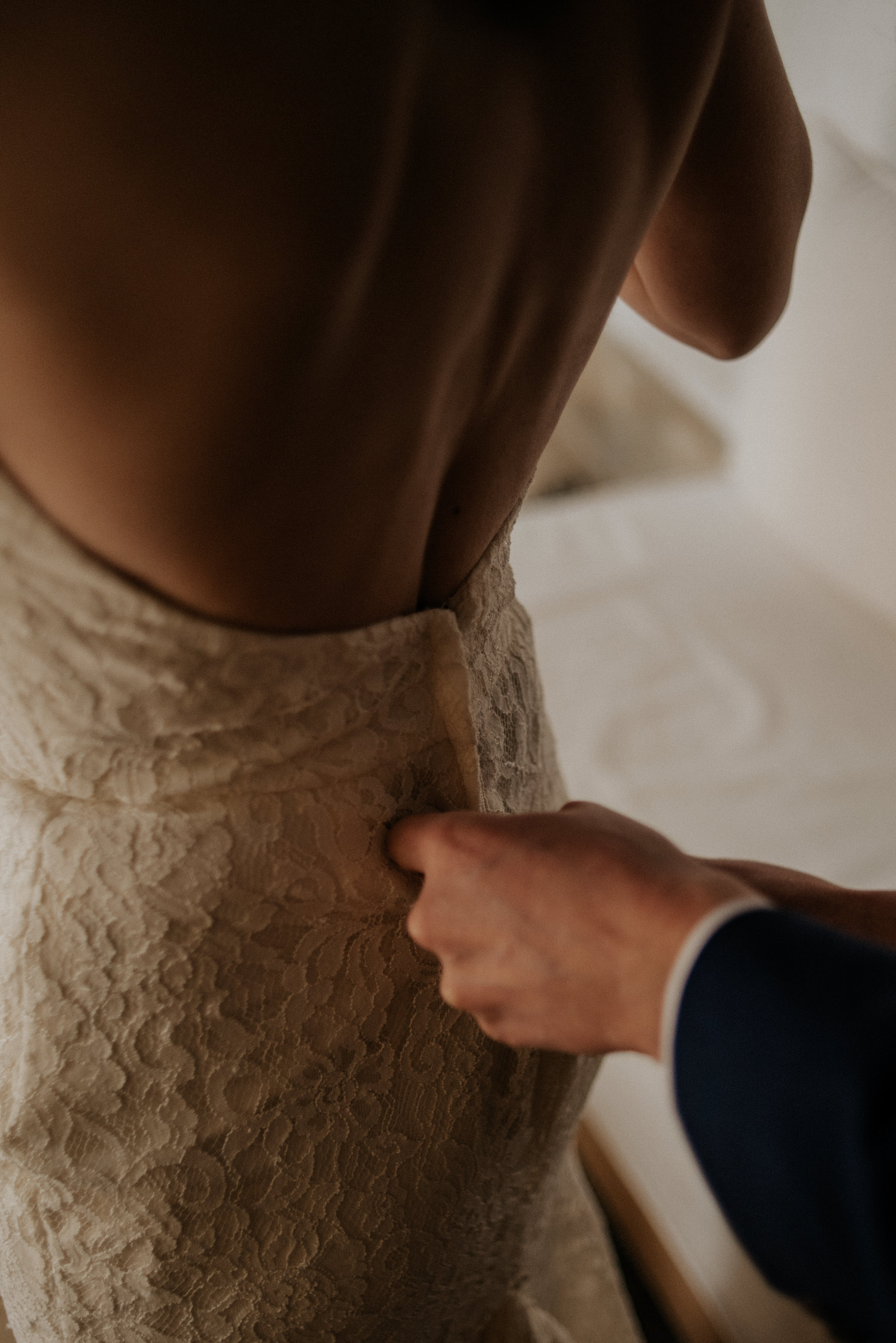 Groom doing up dress of bride