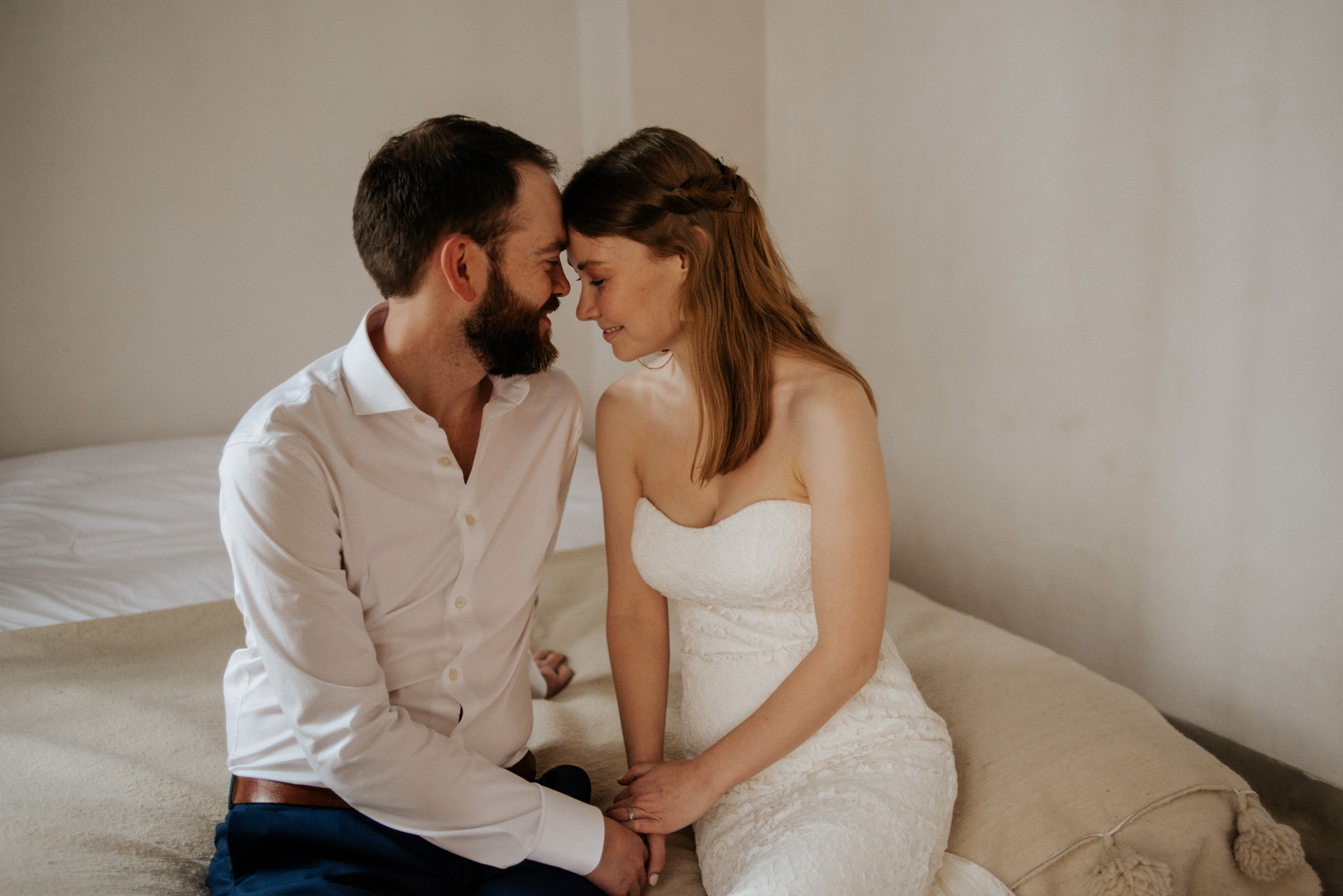 Bride and groom having a moment together sitting on bed before their elopement