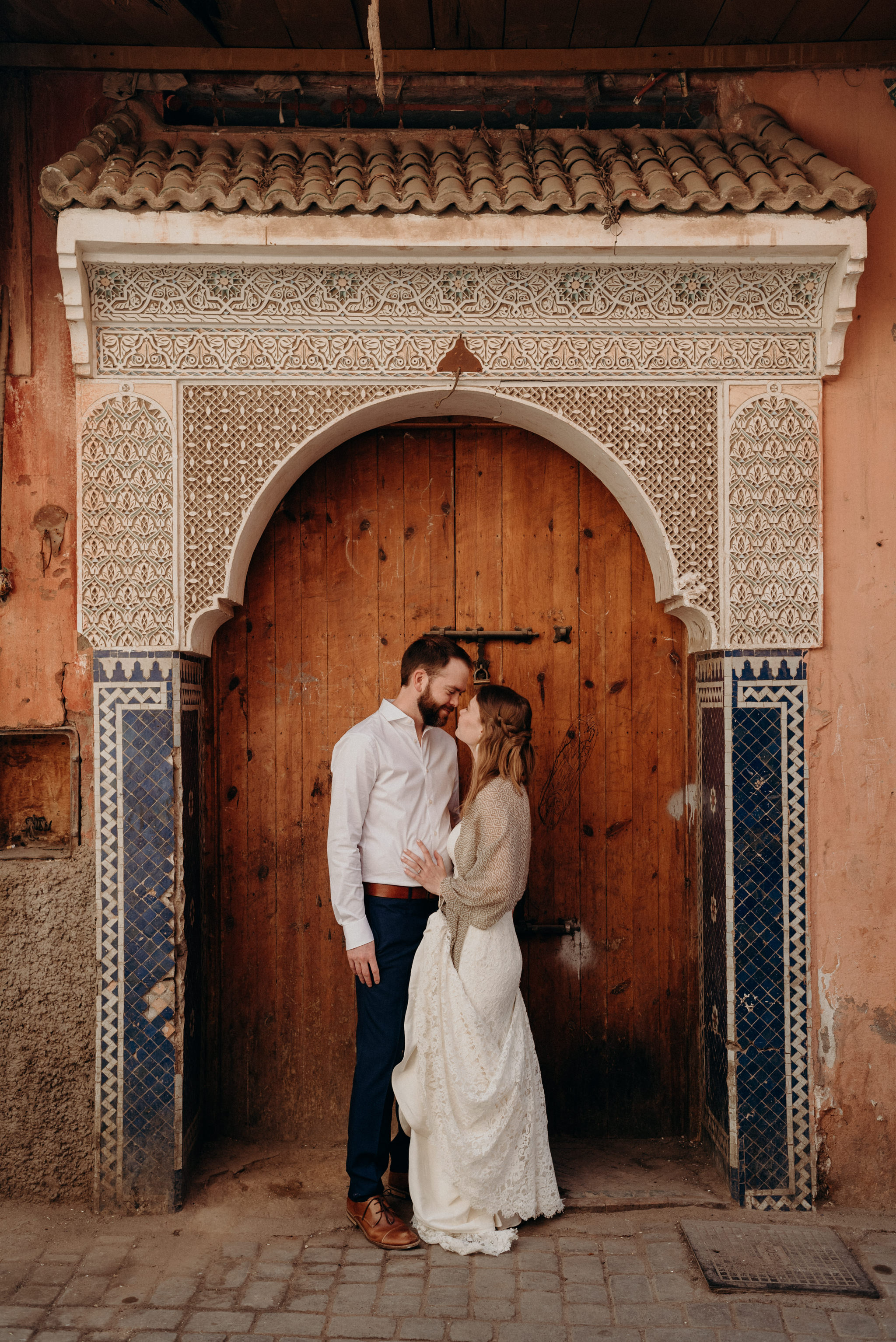 bride and groom standing in front of detailed doorway in Marrakech medina for elopement