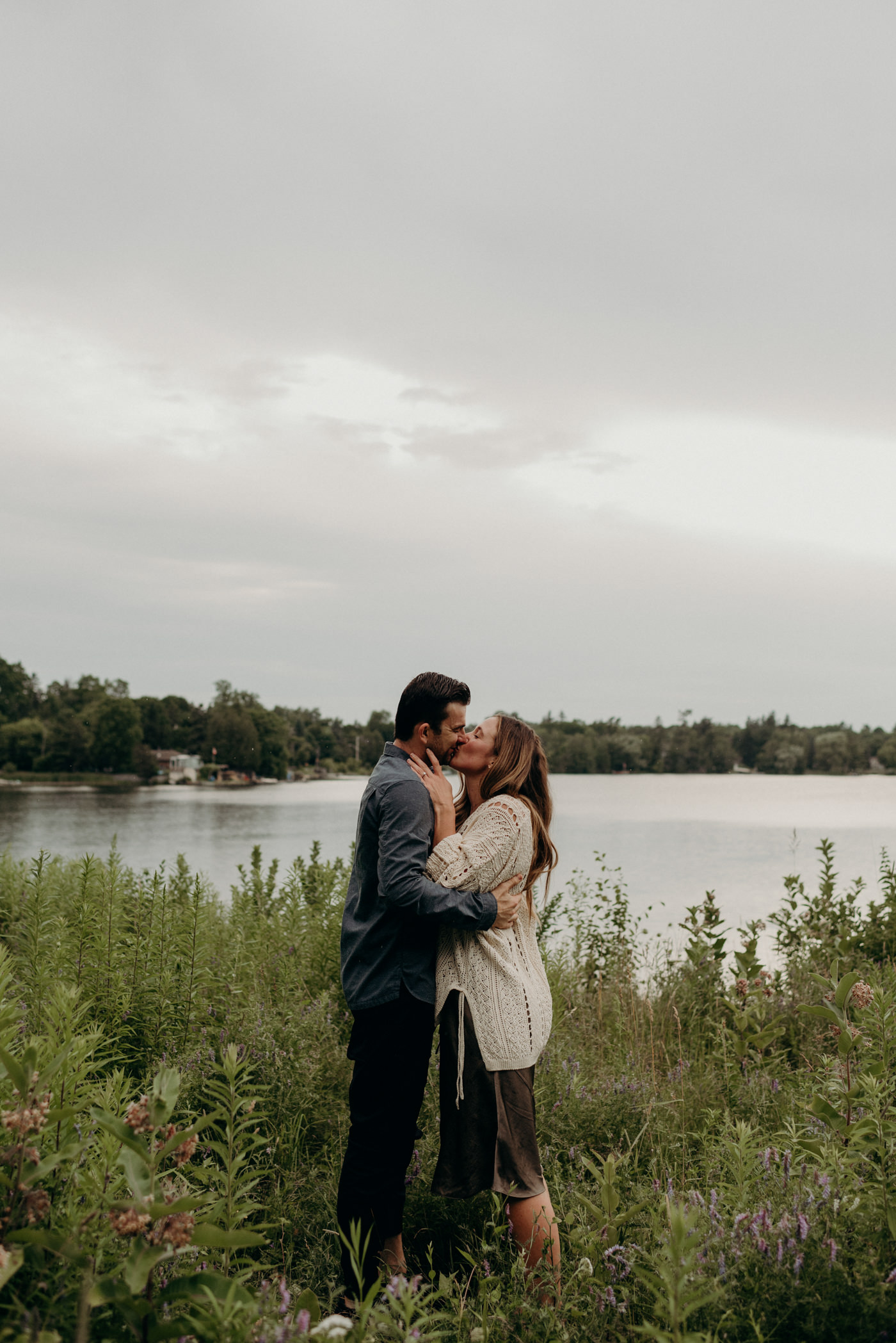 couple kissing in tall grass by lake