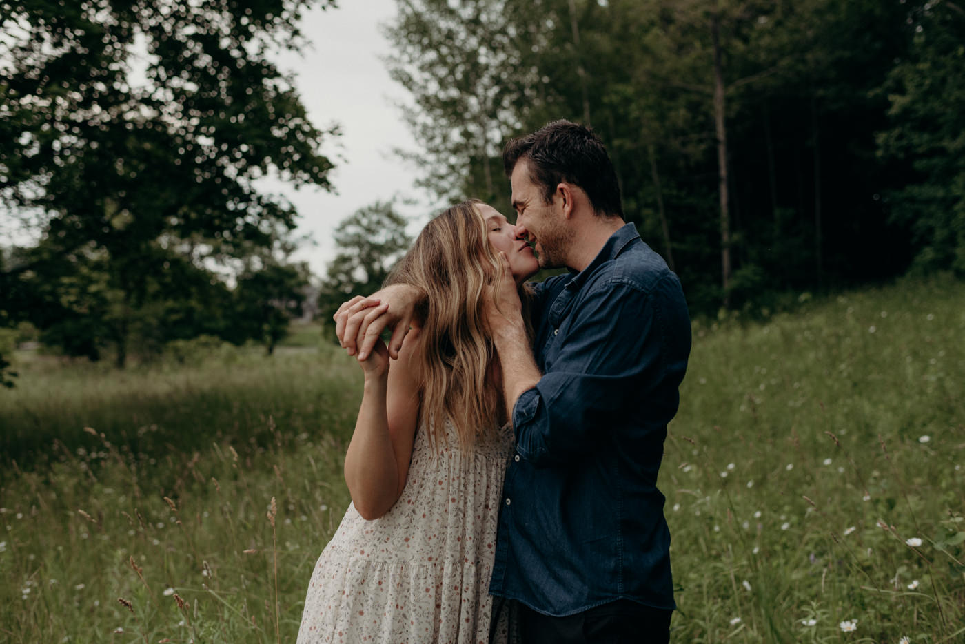 couple in passionate kiss in field of flowers and grass