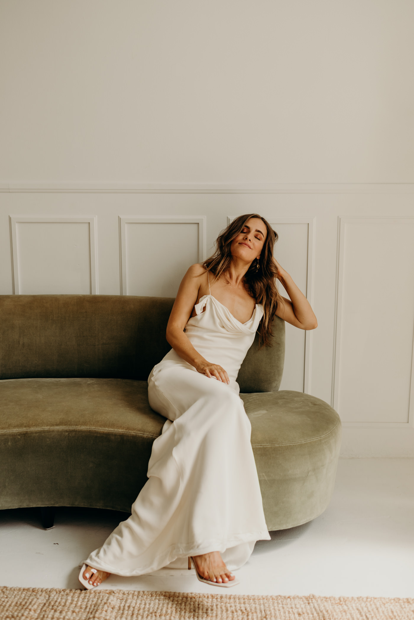 bride on green velvet couch wearing Savannah Miller bridal