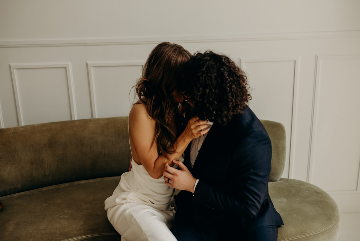 bride and groom kissing on green velvet couch. Midcentury loft elopement at Lovt Studio East in Toronto