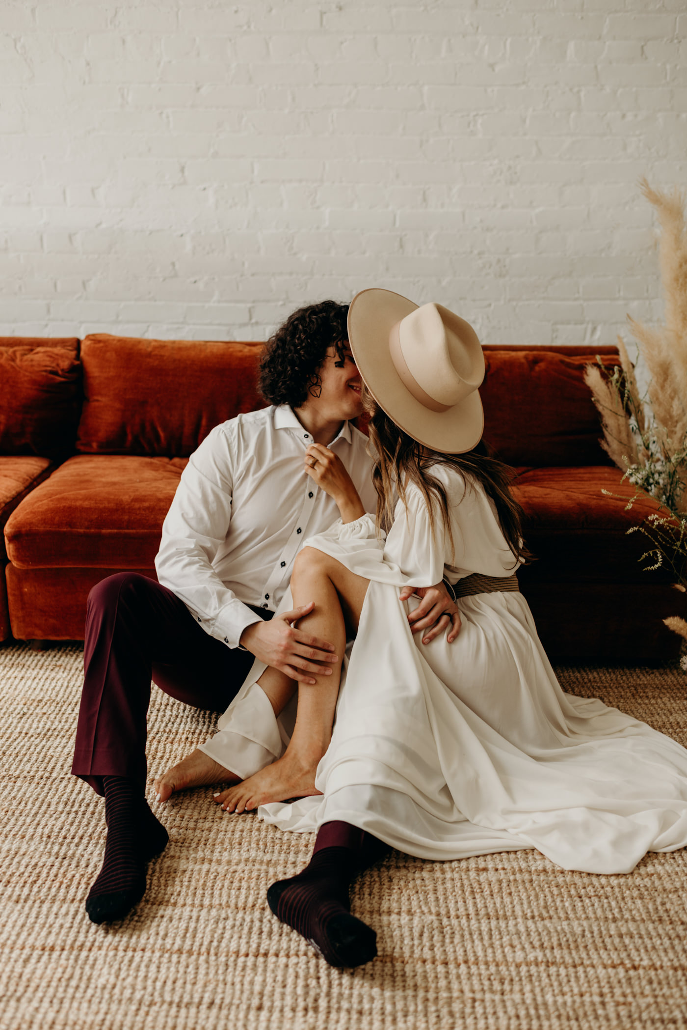 bohemian couple sitting on floor of loft kissing