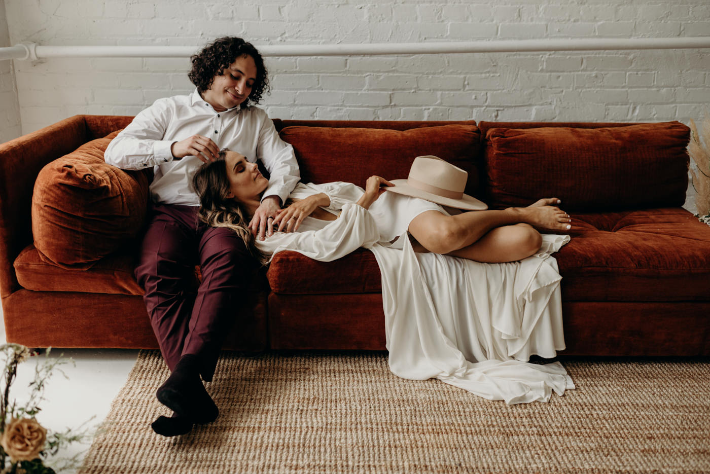 bride lying down on grooms lap on velvet couch in cool midcentury loft elopement in Toronto