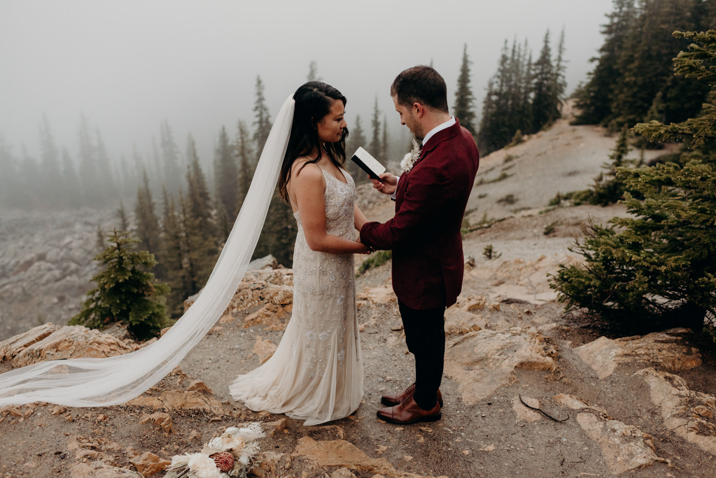 groom reads vows to bride on a rainy morning in Banff National Park