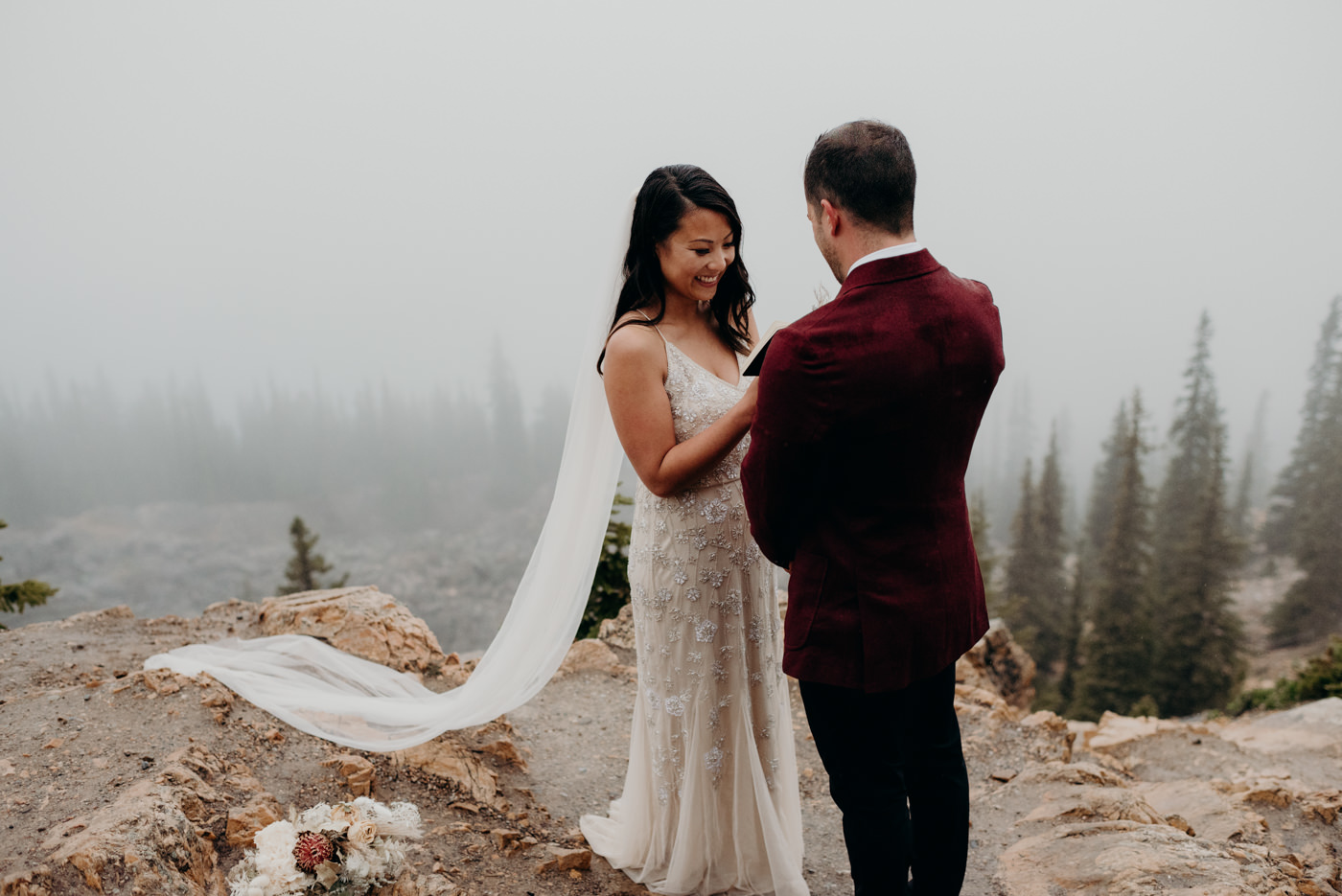 bride smiling and reading vows to groom in the mountains