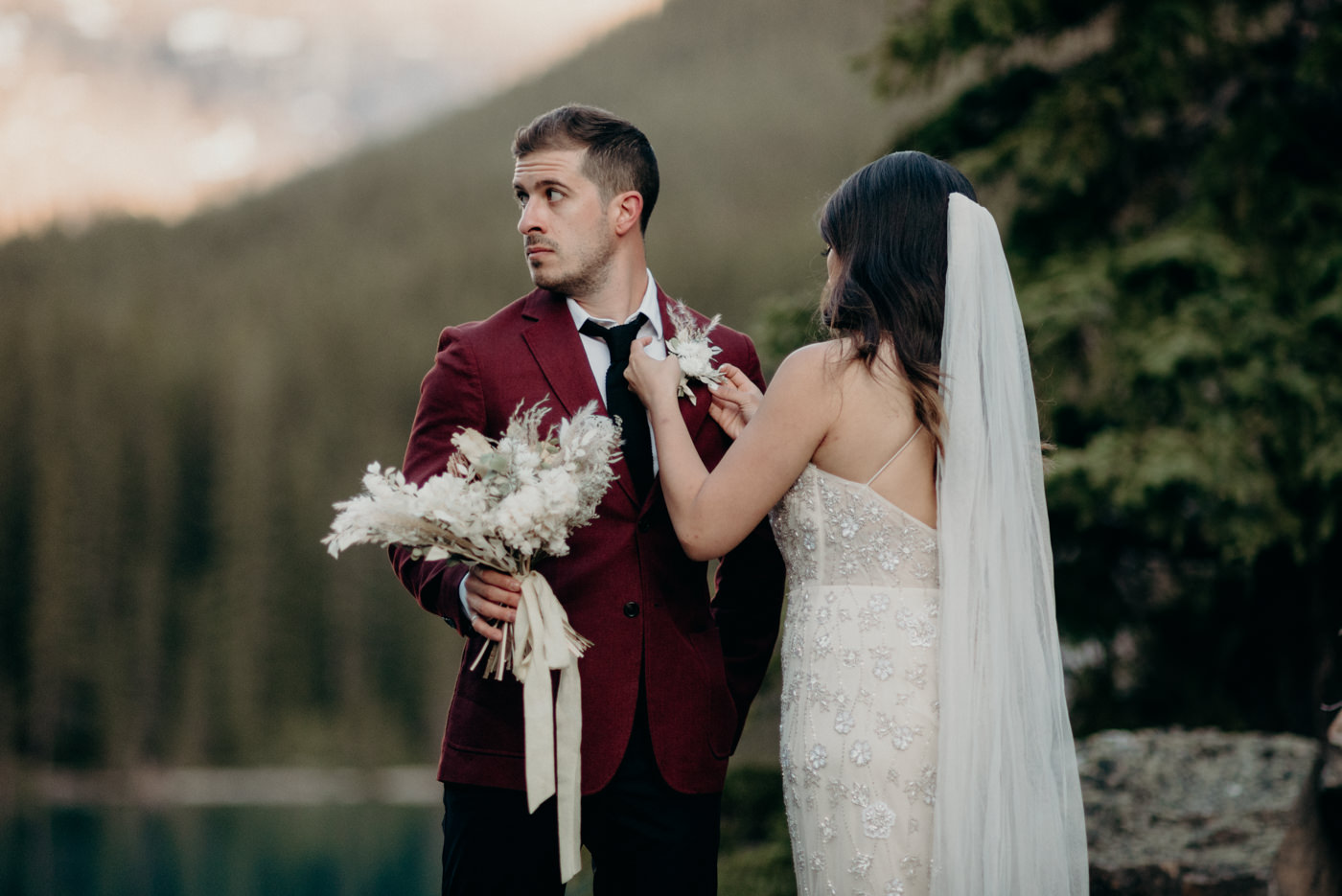 bride adjusting grooms boutonniere, Moraine Lake elopement