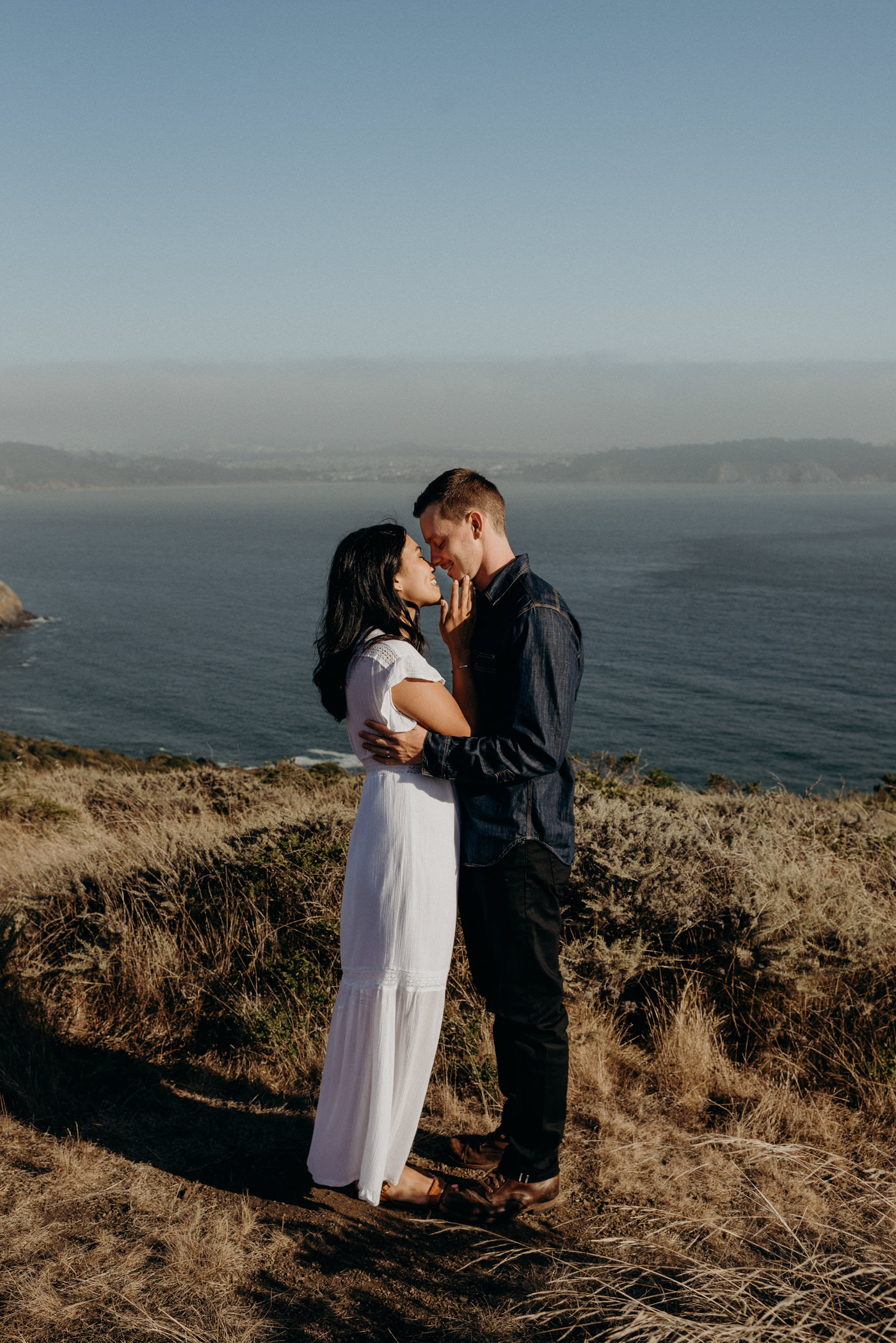 couple hugging and about to kiss while standing on cliff