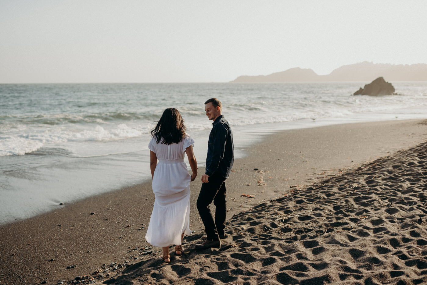 Couple running and chasing each other on the beach at sunset