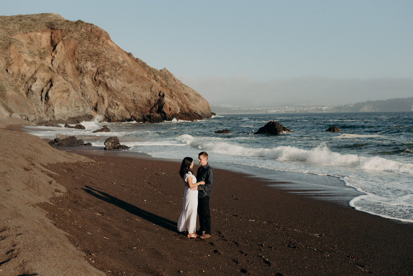 Couple standing on beach hugging at sunset