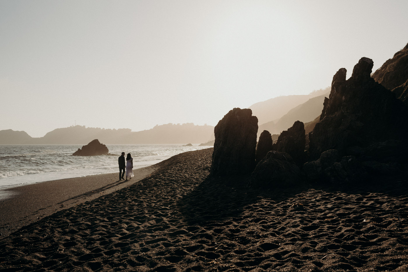 Couple walking on beach at sunset at Marin Headlands