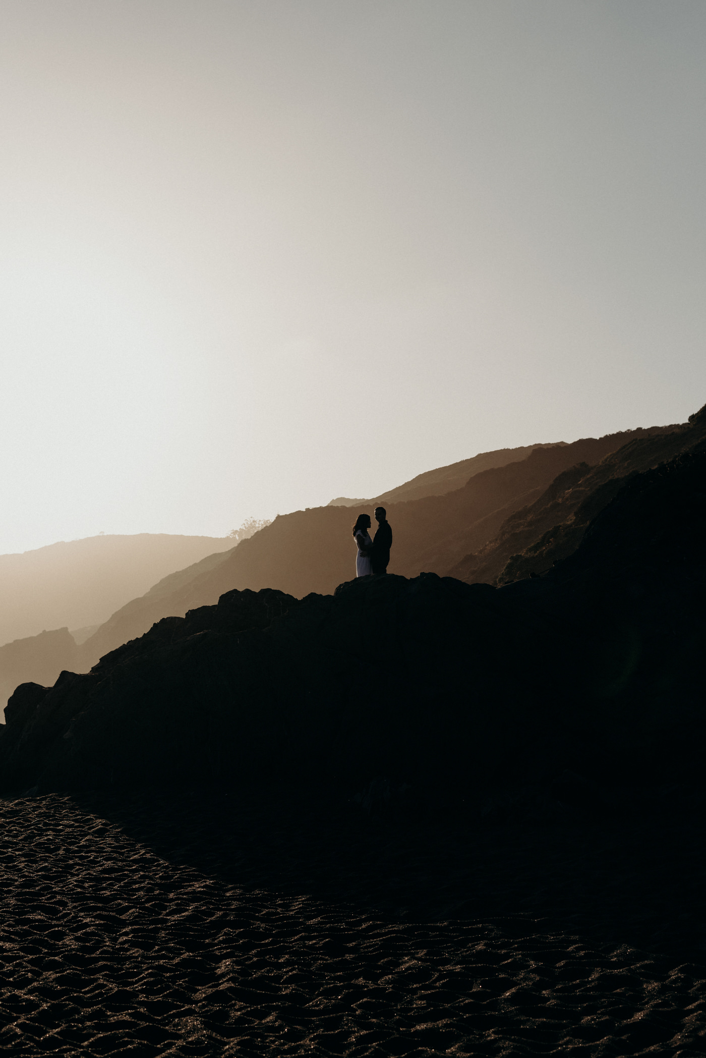 Couple standing on rocks at sunset at Marin Headlands