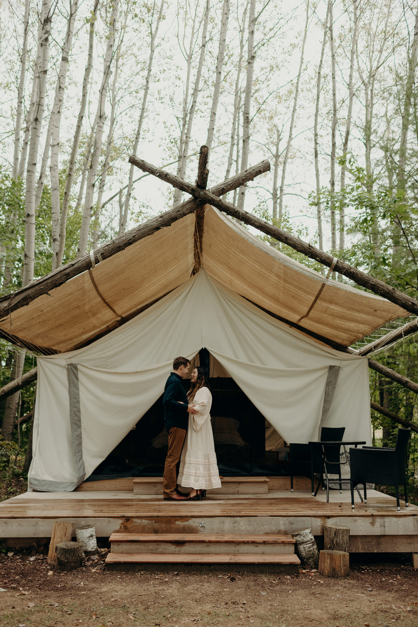 Couple standing on deck of their canvas tent