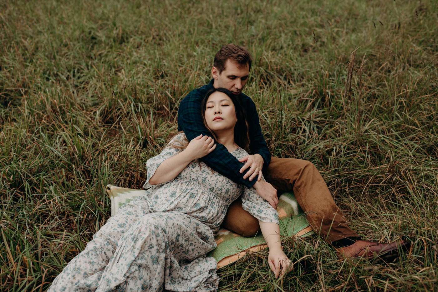 Couple lying in a field during their dreamy Whispering Springs engagement session