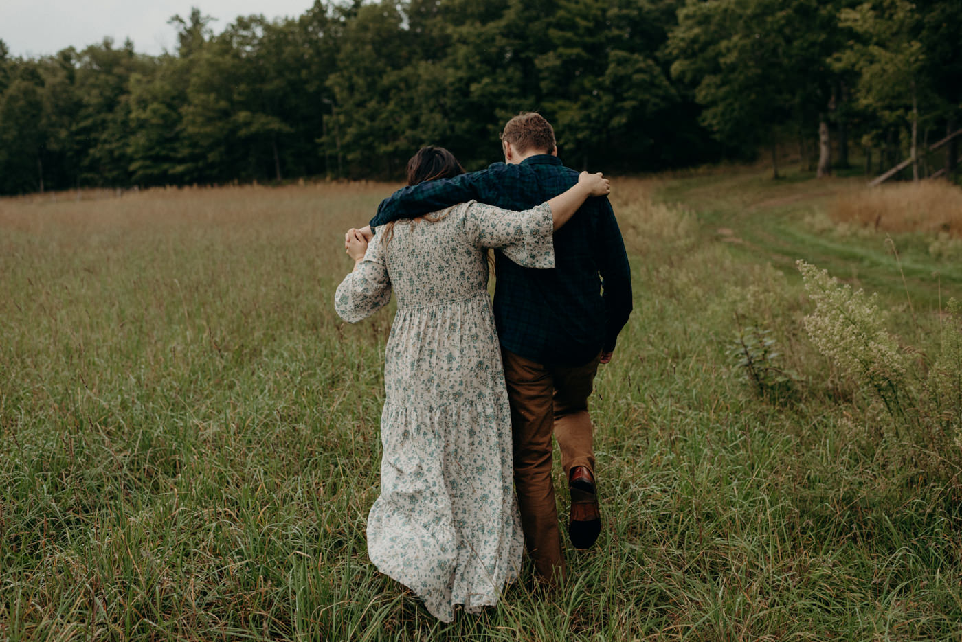 Couple walking with arounds around each other in a field of grass