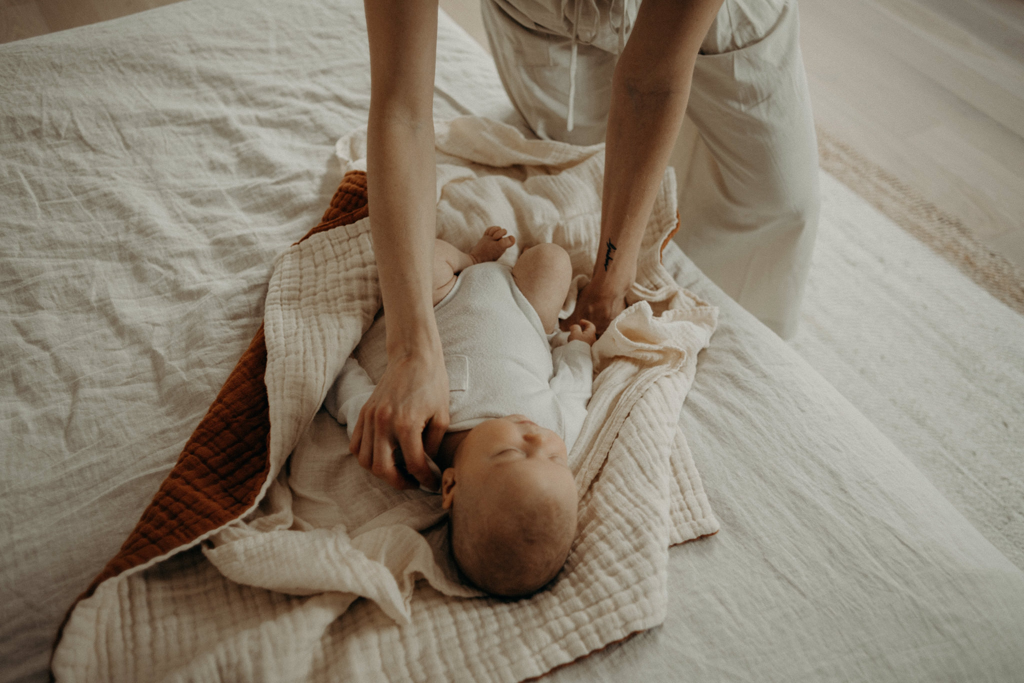 mother wrapping up newborn son on the bed