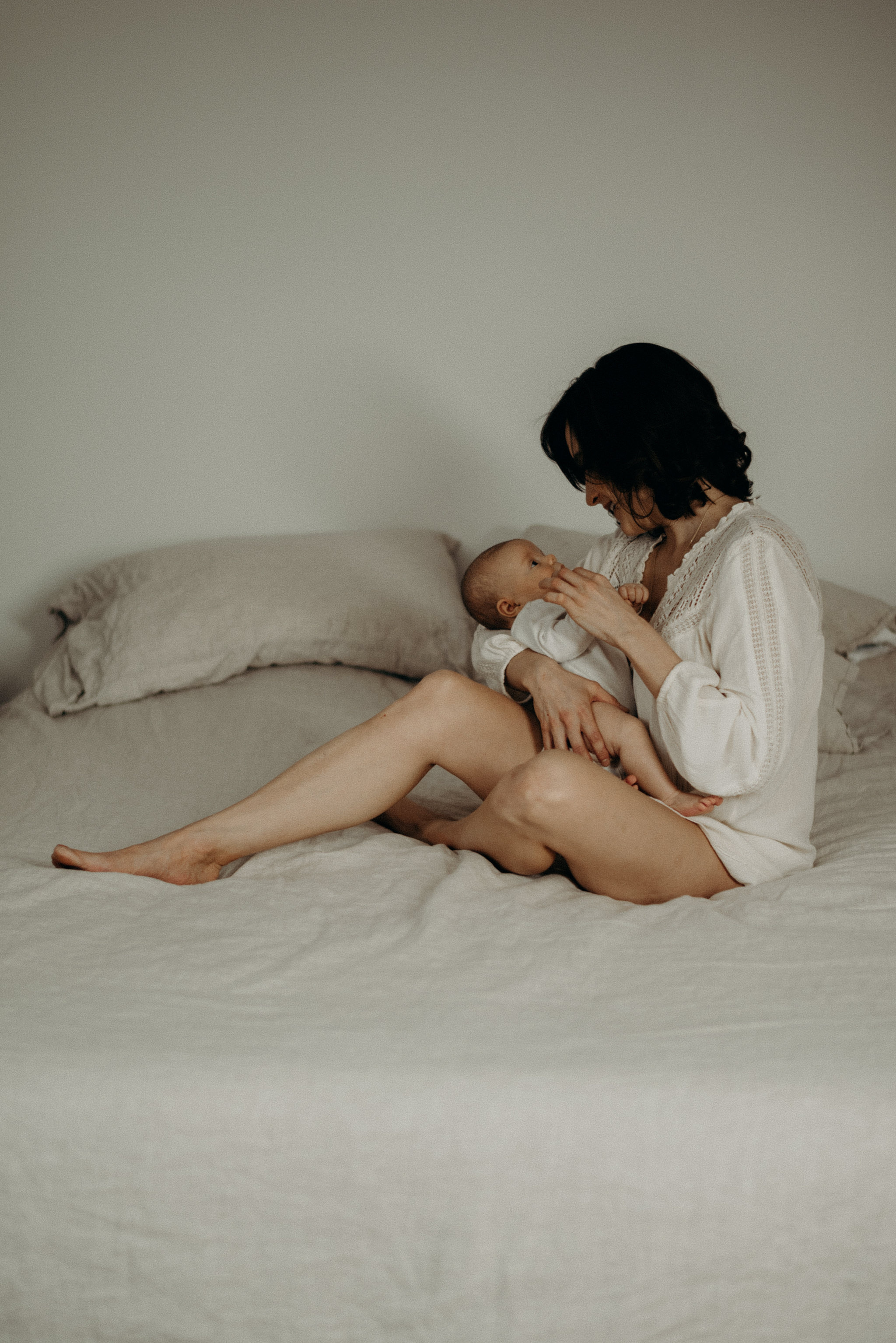 mother holding her newborn baby on the bed