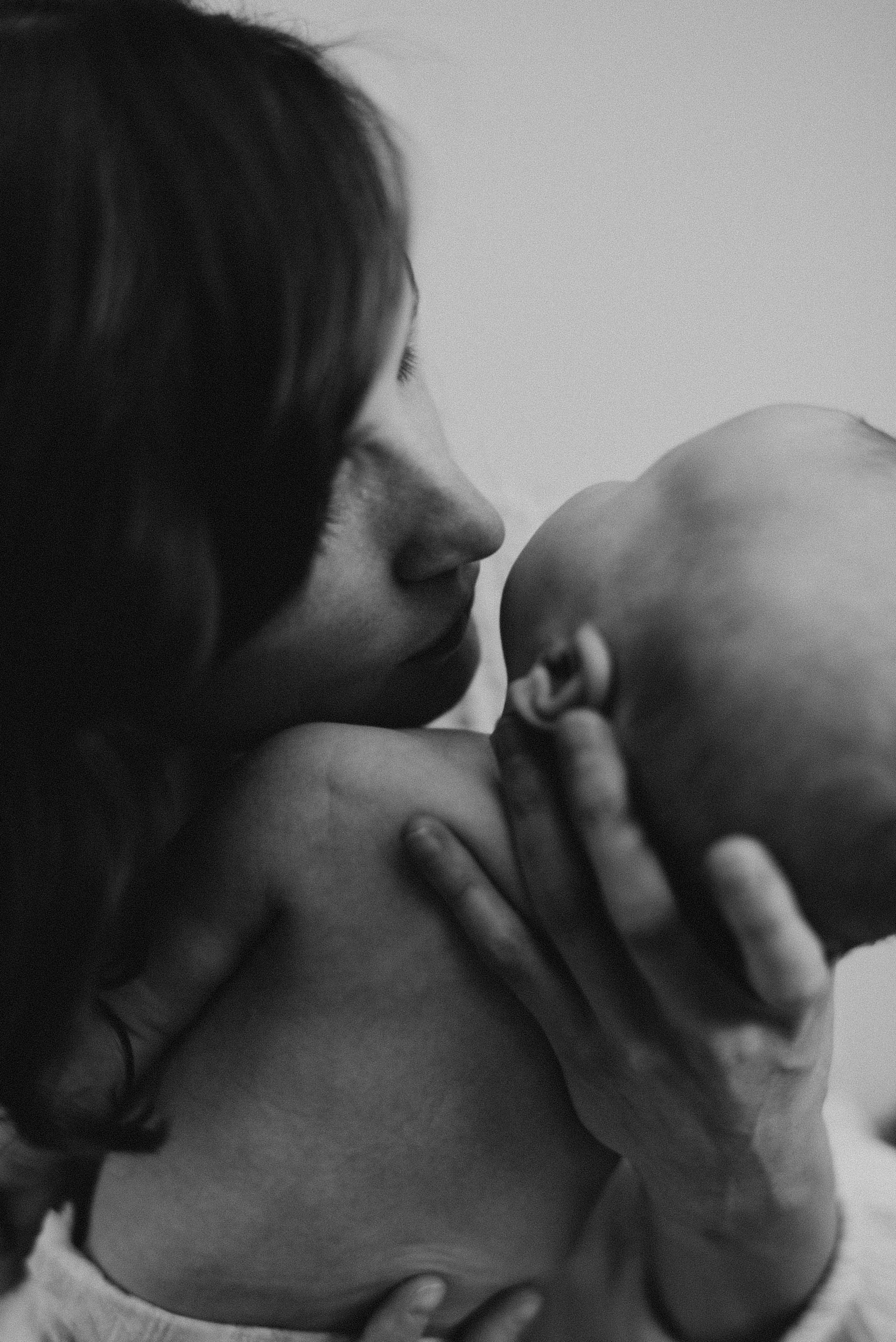 mother kissing newborn baby