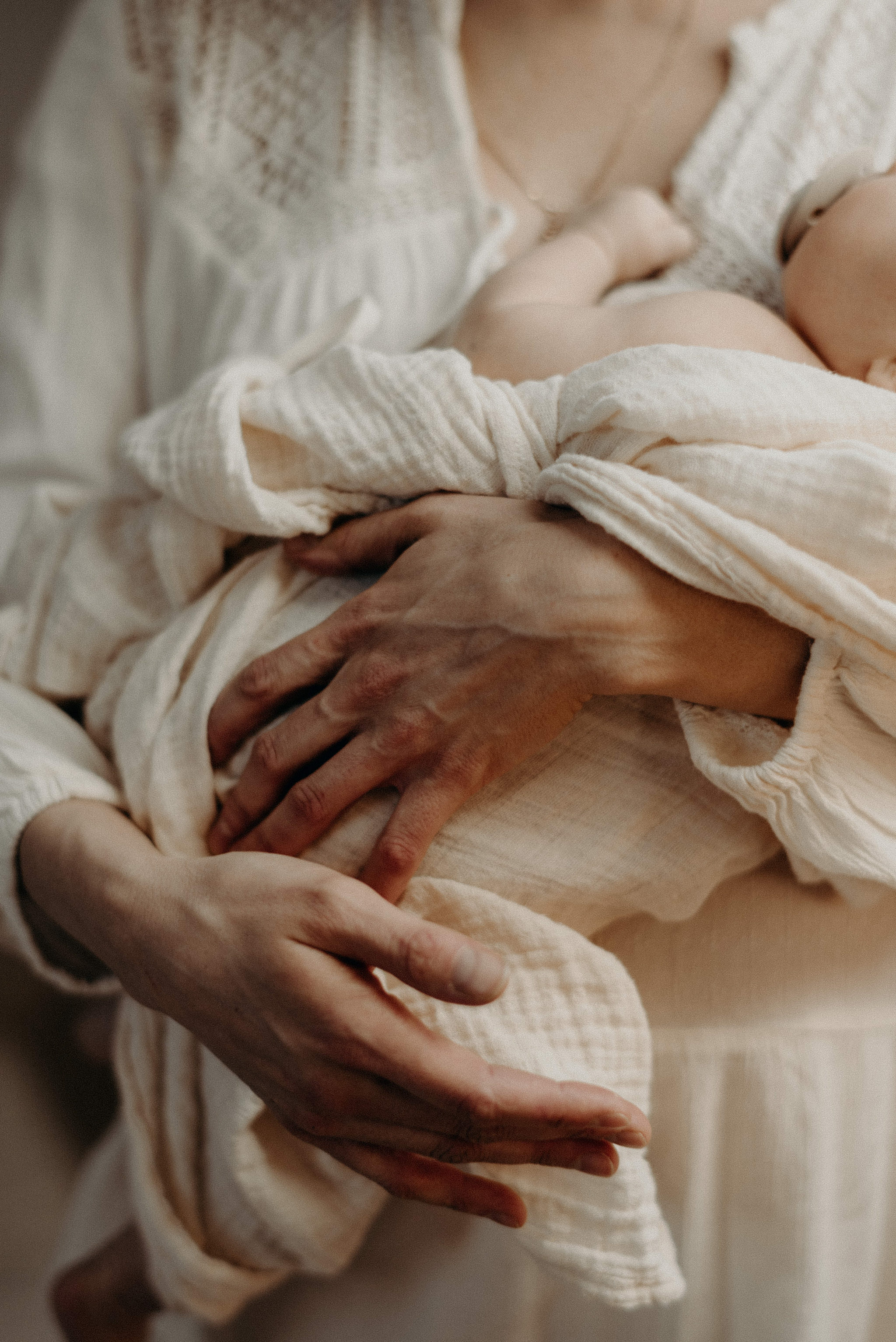 mother dressed in neutrals holding newborn baby