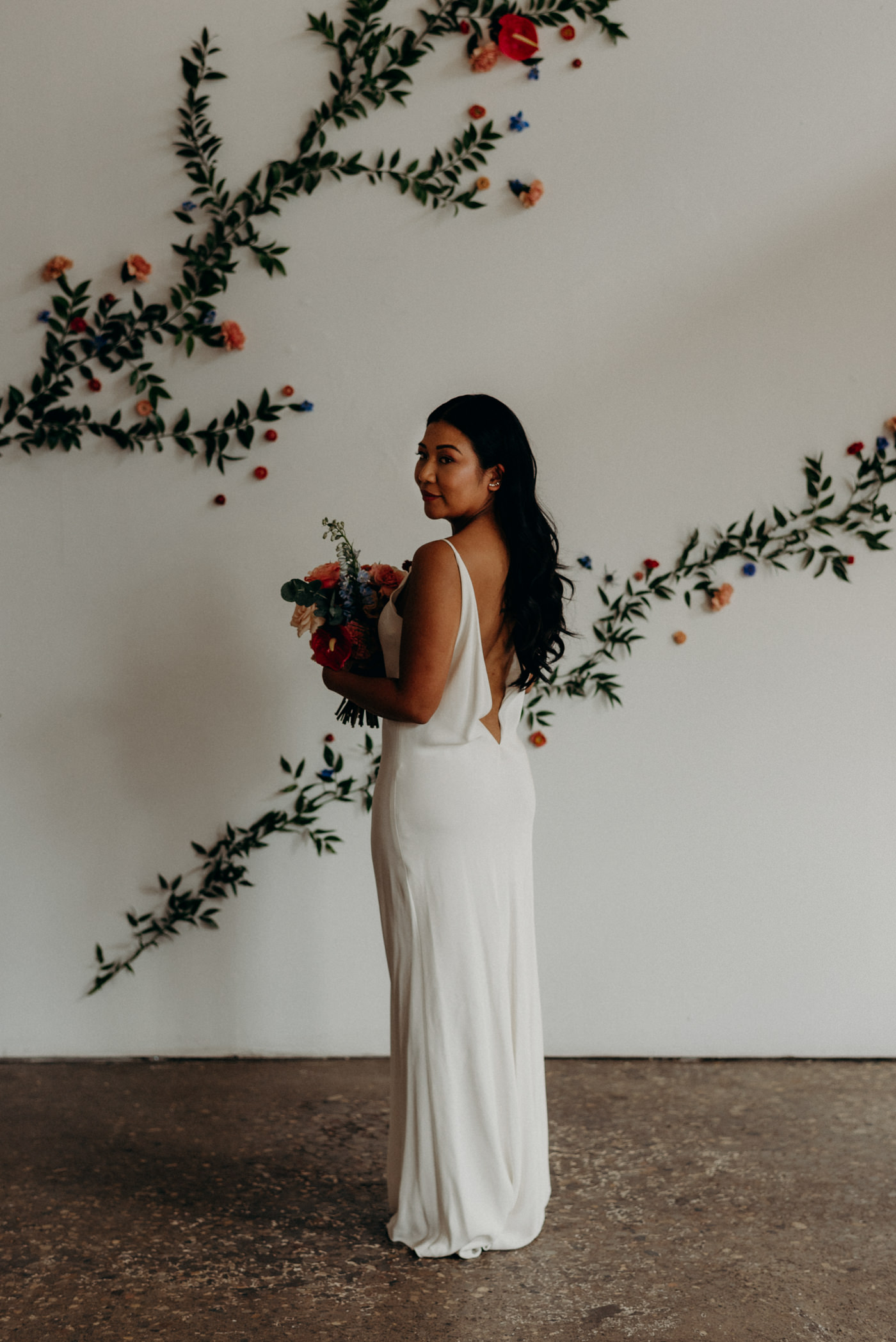 Bride in front of floral wall at Airship37 Wedding