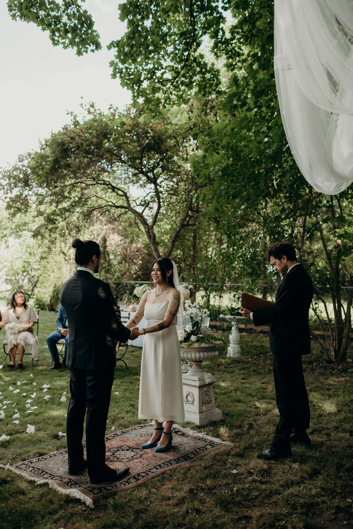 bride and groom holding hands while standing on carpet for outdoor backyard wedding ceremony