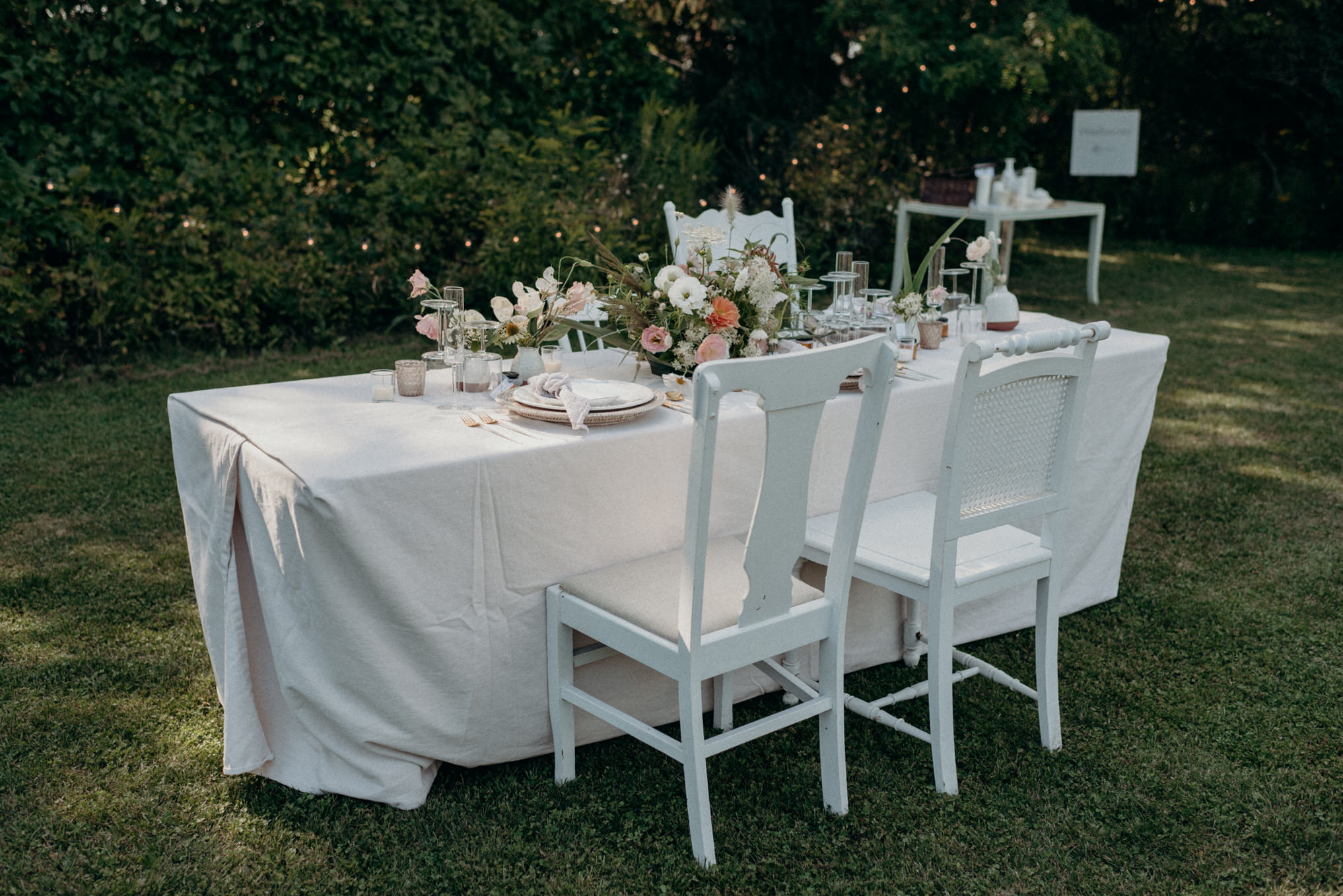 outdoor wedding reception on grass, table setting with string lights on trees