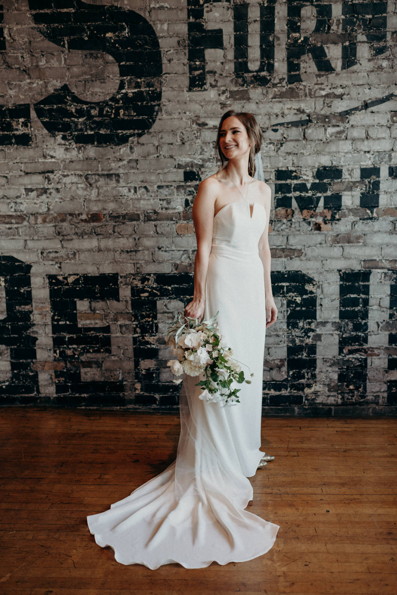 bride standing against brick wall at The Burroughes