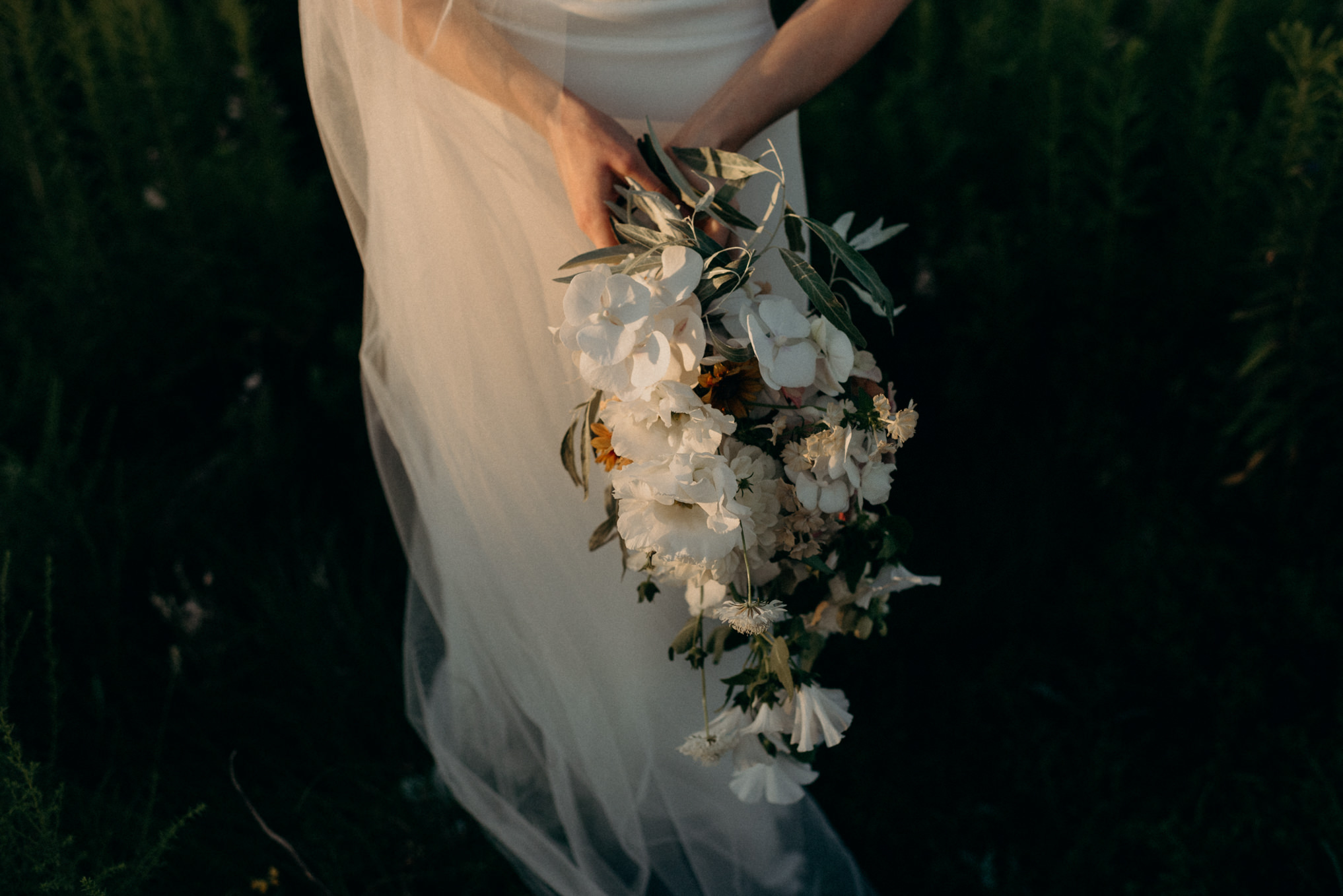 bride holding bouquet in sunlight from sunset