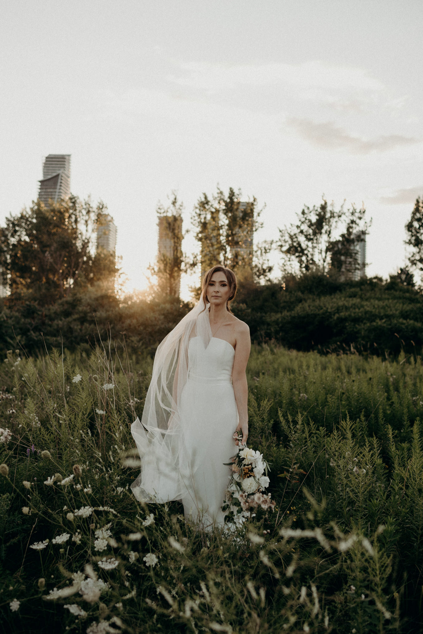 bride with sunset and condo buildings in background at Humber Bay. Toronto elopement portraits.
