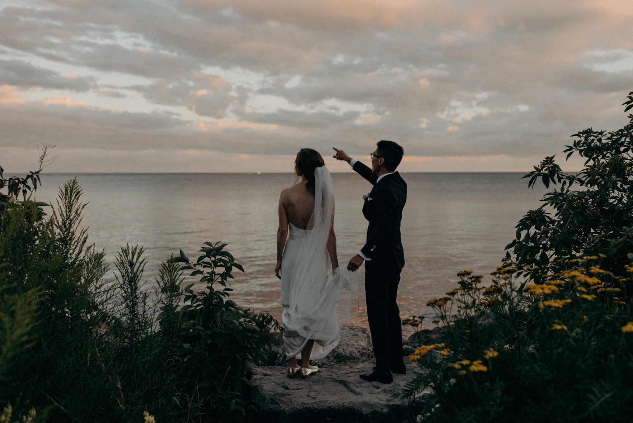 Bride and groom looking out onto Lake Ontario at sunset. Humber Bay elopement in Toronto