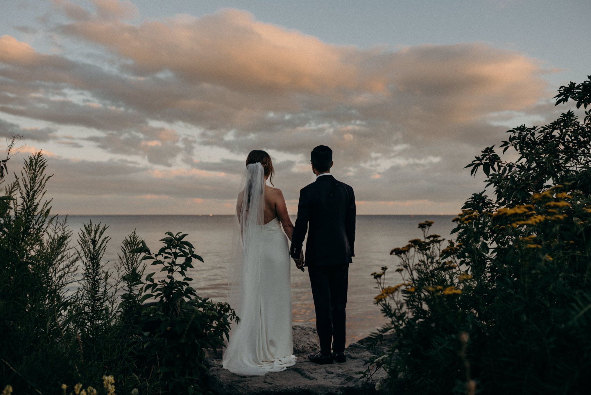 bride and groom looking out onto water at sunset at Humber bay. Toronto elopement.