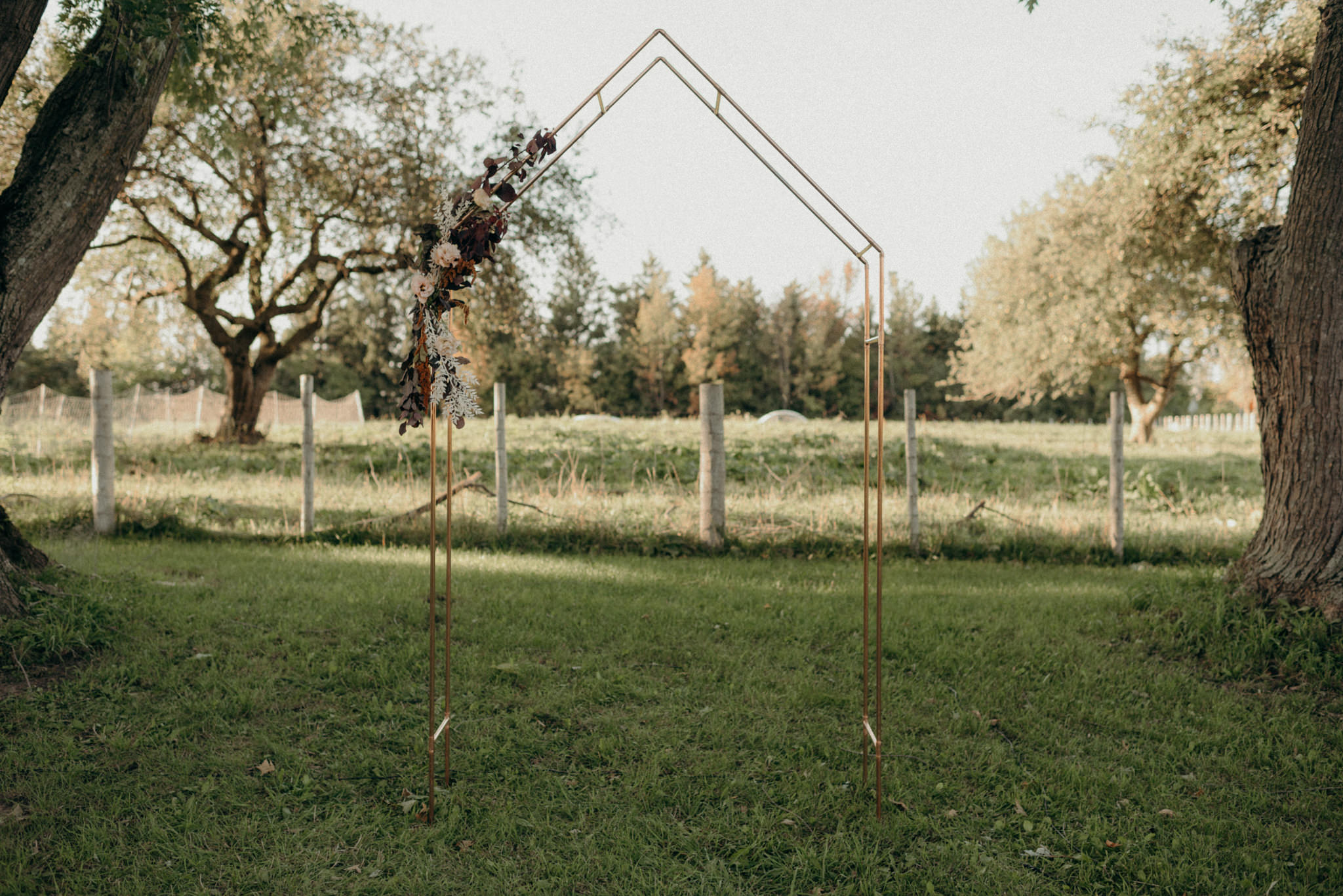 simple copper metal wedding ceremony arch with flowers