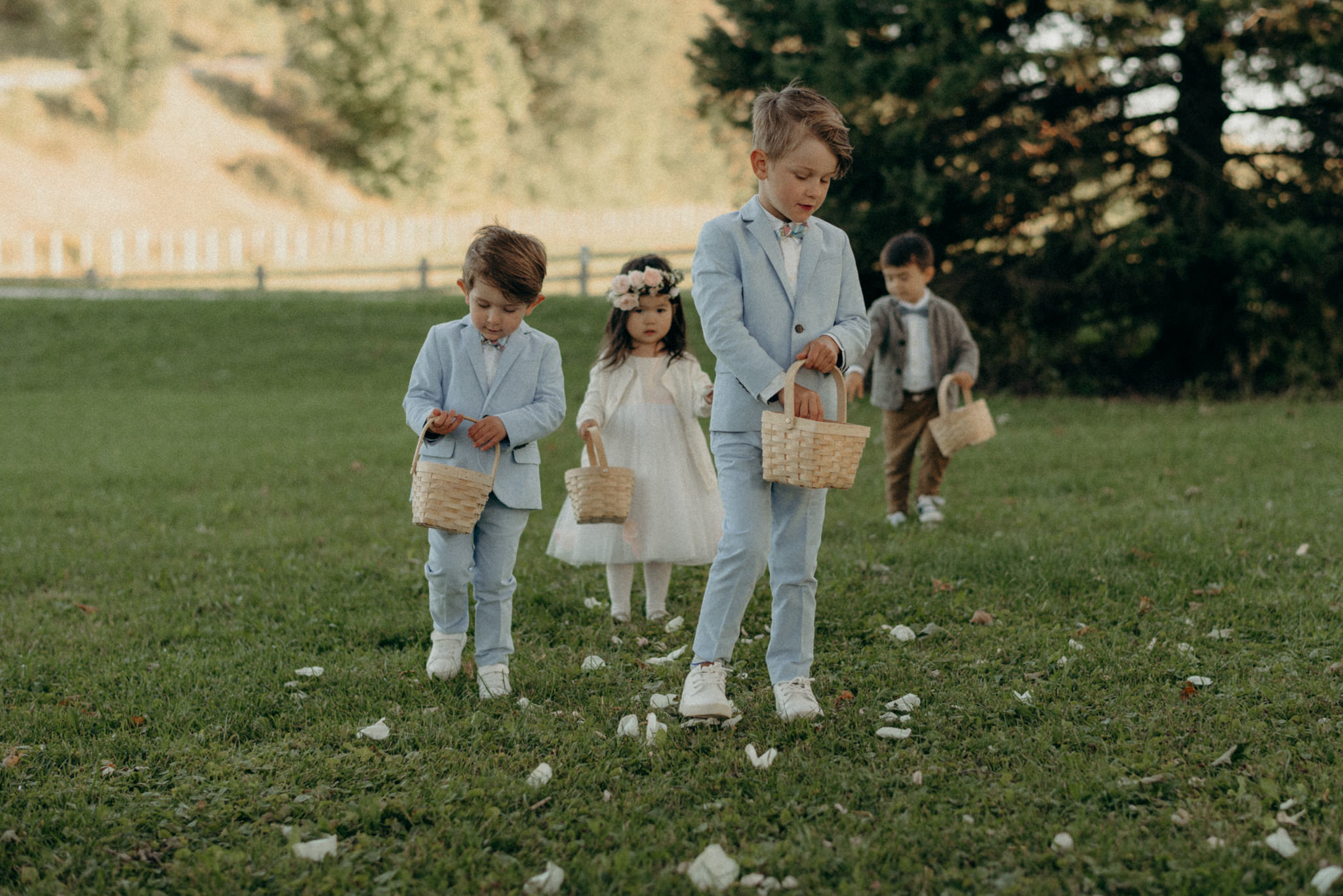 cute flower boys and flower girl walking down grassy aisle