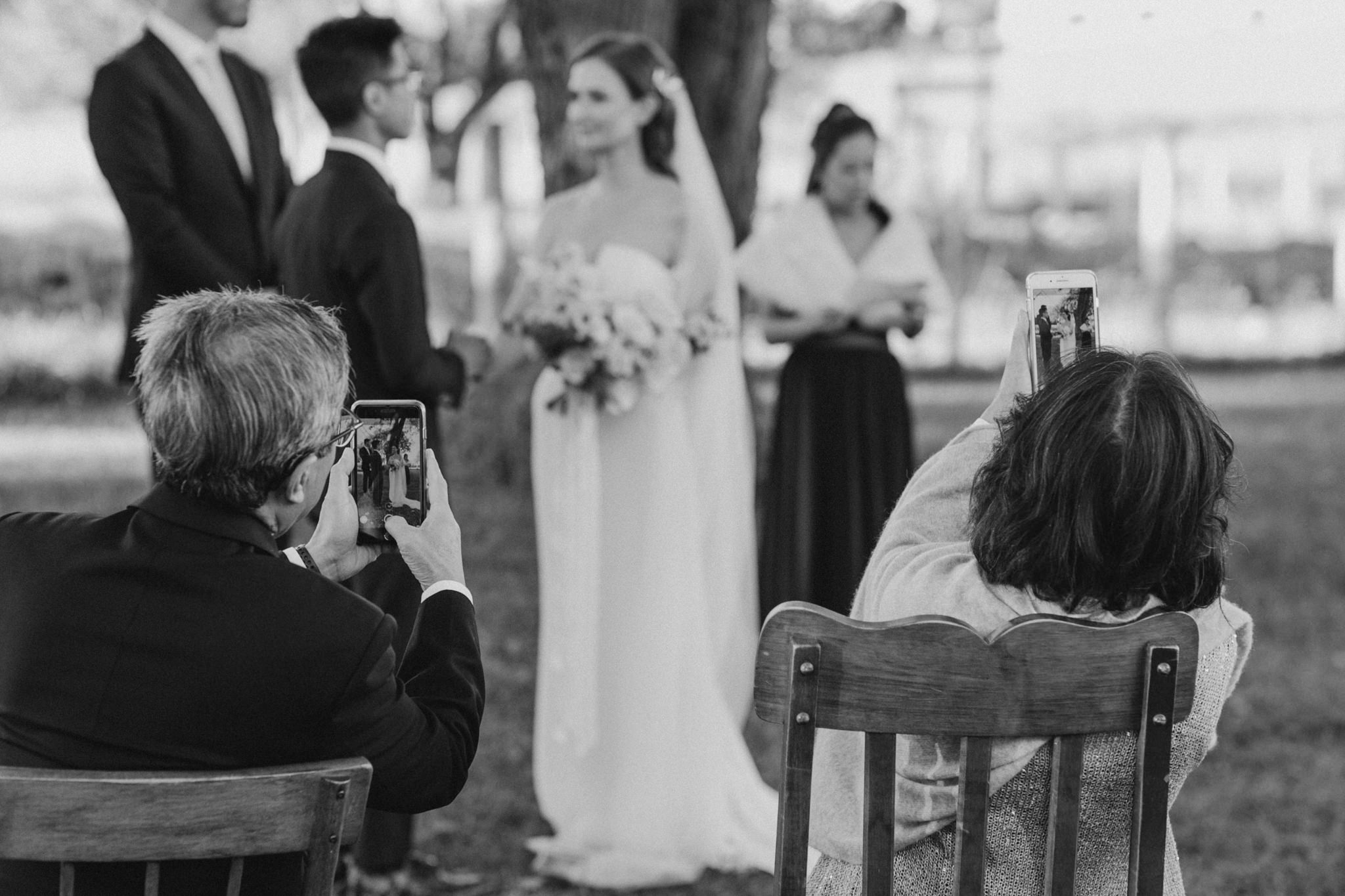 guests taking pictures with cellphones at wedding