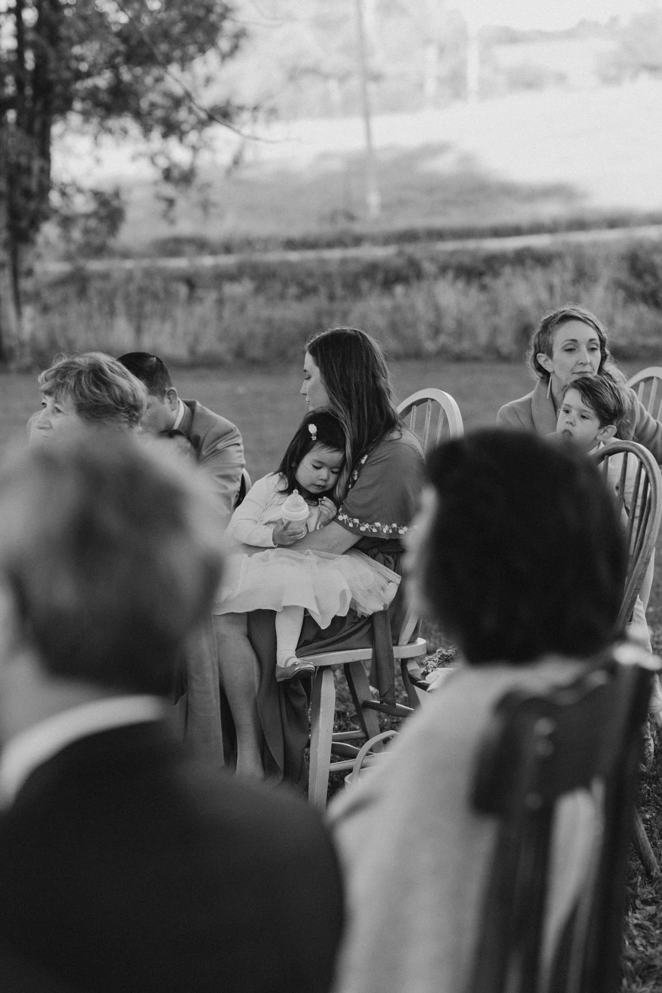 little girl asleep on mothers lap at wedding