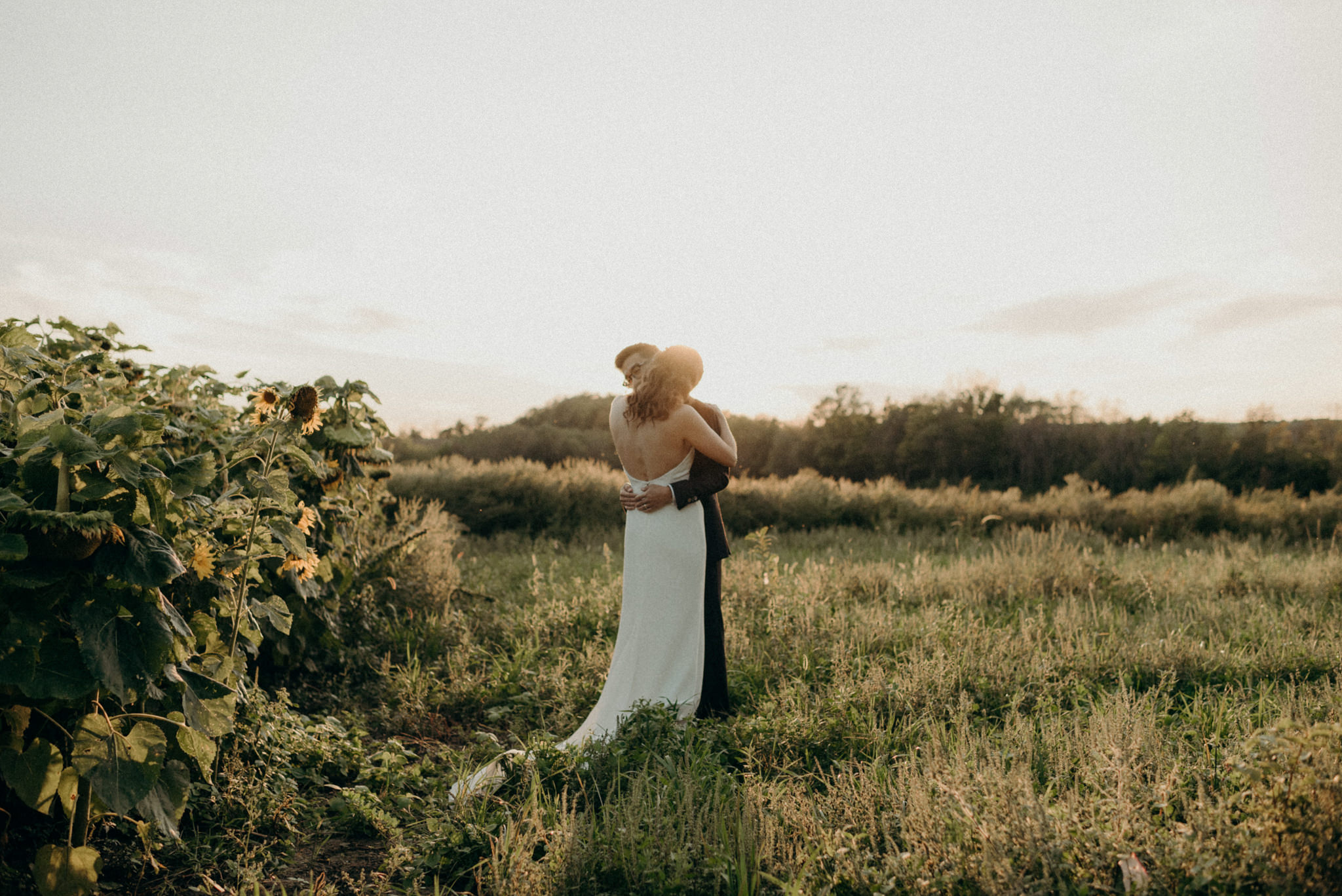 Couple hugging in a field at sunset. Good Family Farms wedding.